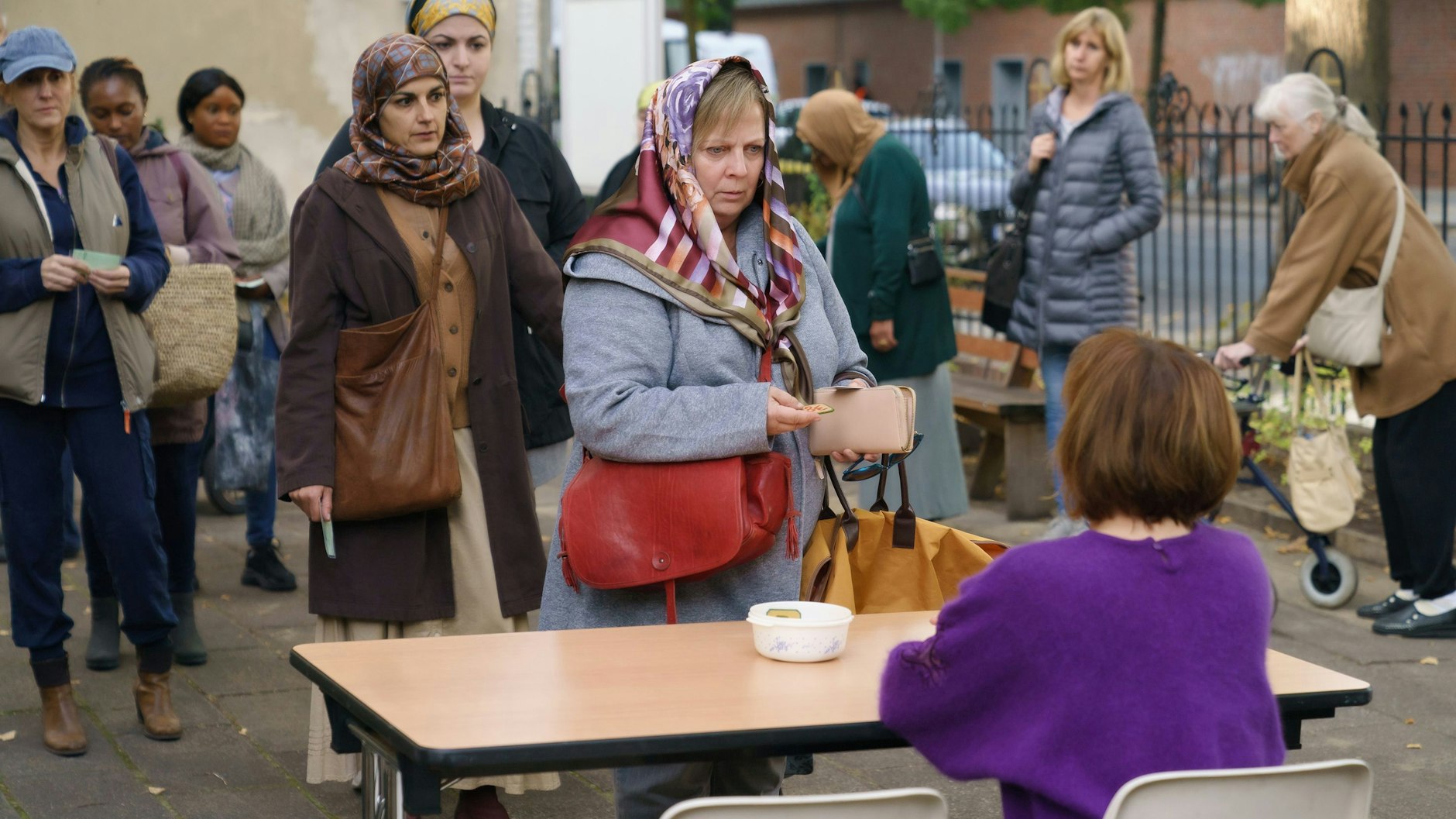 Szene aus „Tina mobil“, in der Tina (Gabriela Maria Schmeide)&nbsp; für die Markenausgabe bei der Tafel ansteht. In der Serie geht es um die täglichen Probleme und Sorgen einer dreifachen Mutter in Pankow, die trotz Geldmangel nicht aufgibt.