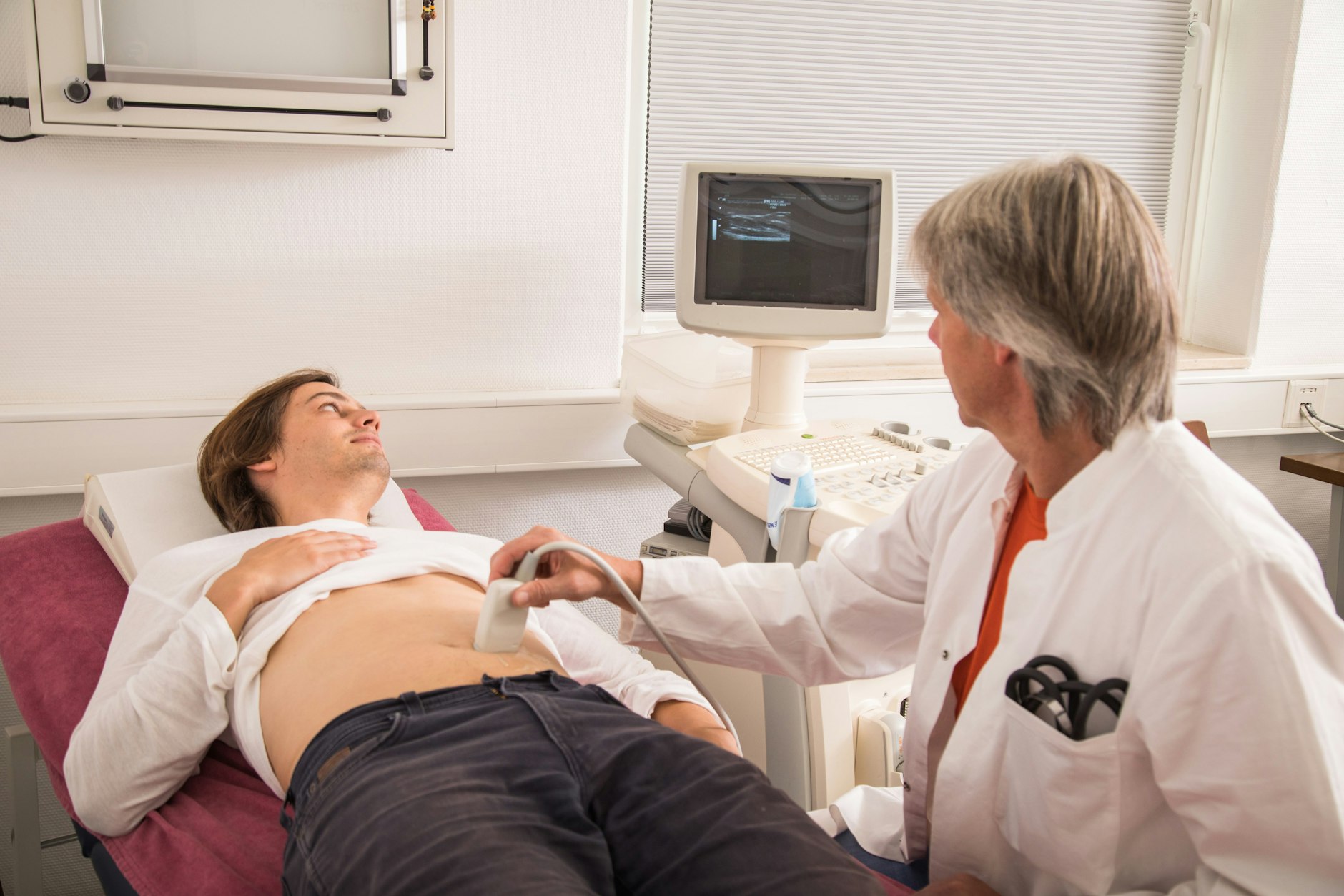 Ein Arzt untersucht per Ultraschall den Bauch eines Patienten.
