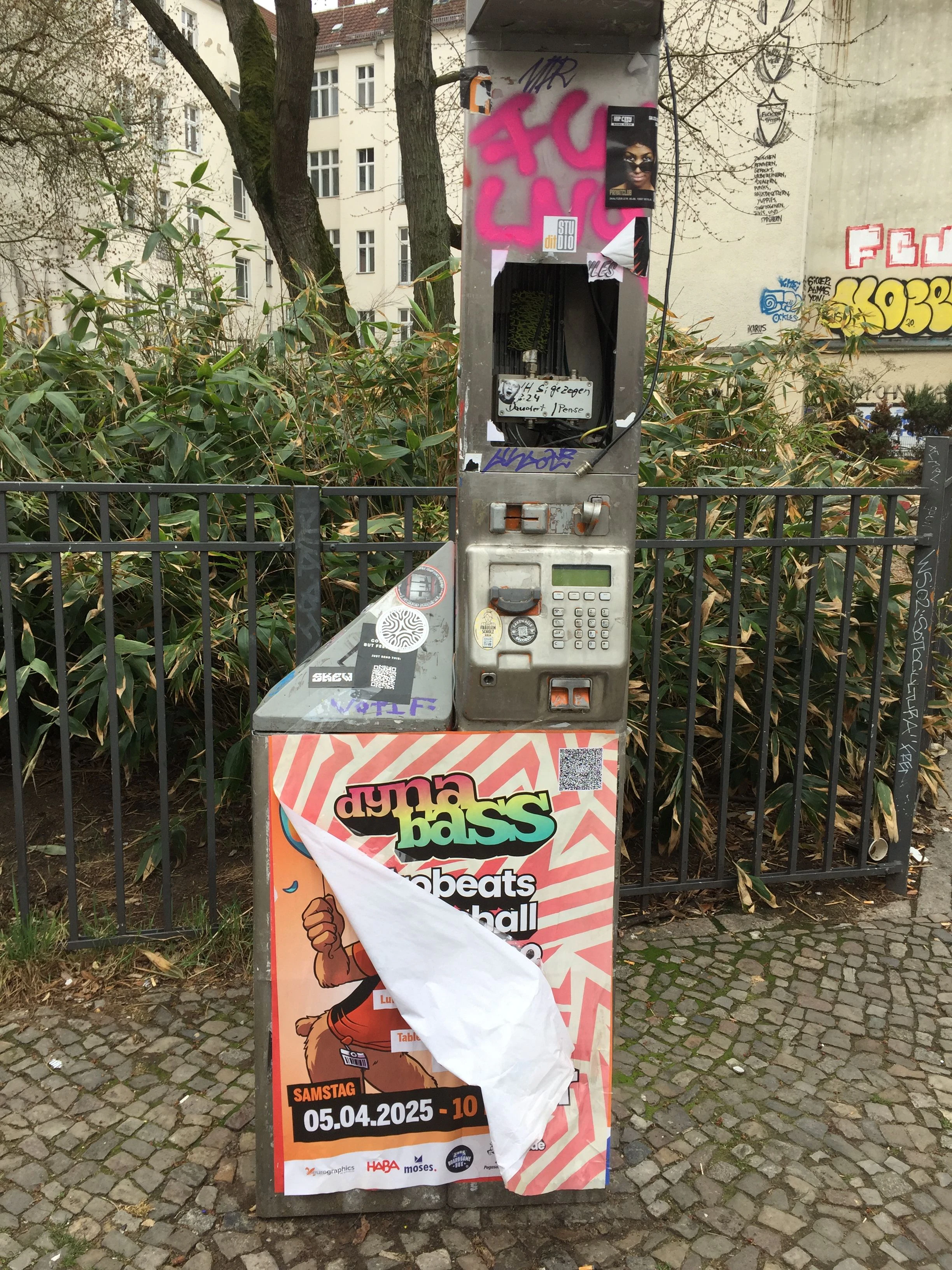 Typisches Berlin-Bild. Ein demoliertes öffentliches Telefon ist mit Plakaten vollgehängt.