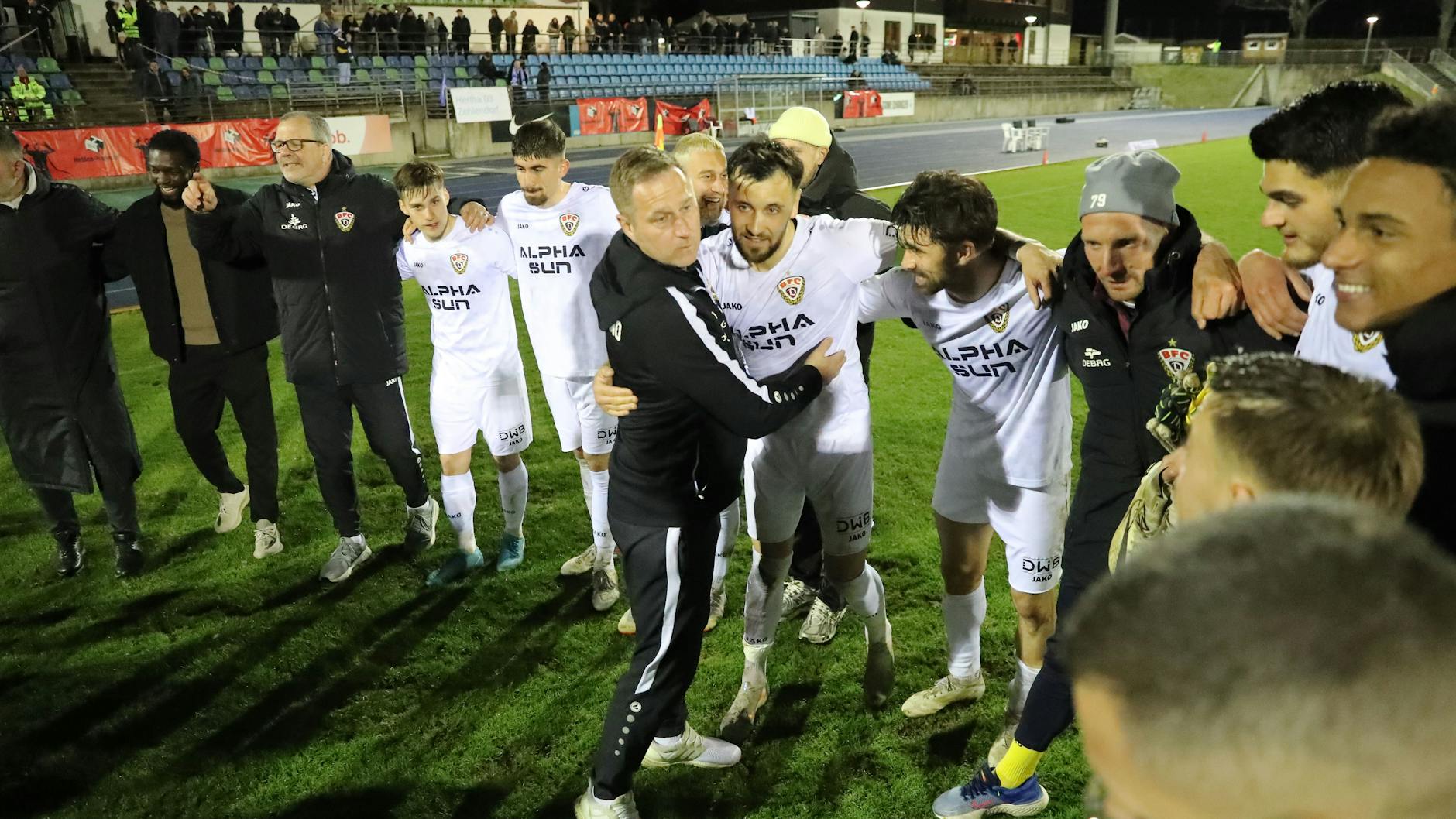 BFC-Trainer Dennis Kutrieb feiert nach dem Sieg in Zehlendorf im Spielerkreis, umarmt Rufat Dadashov, David Haider ist nicht weit weg.