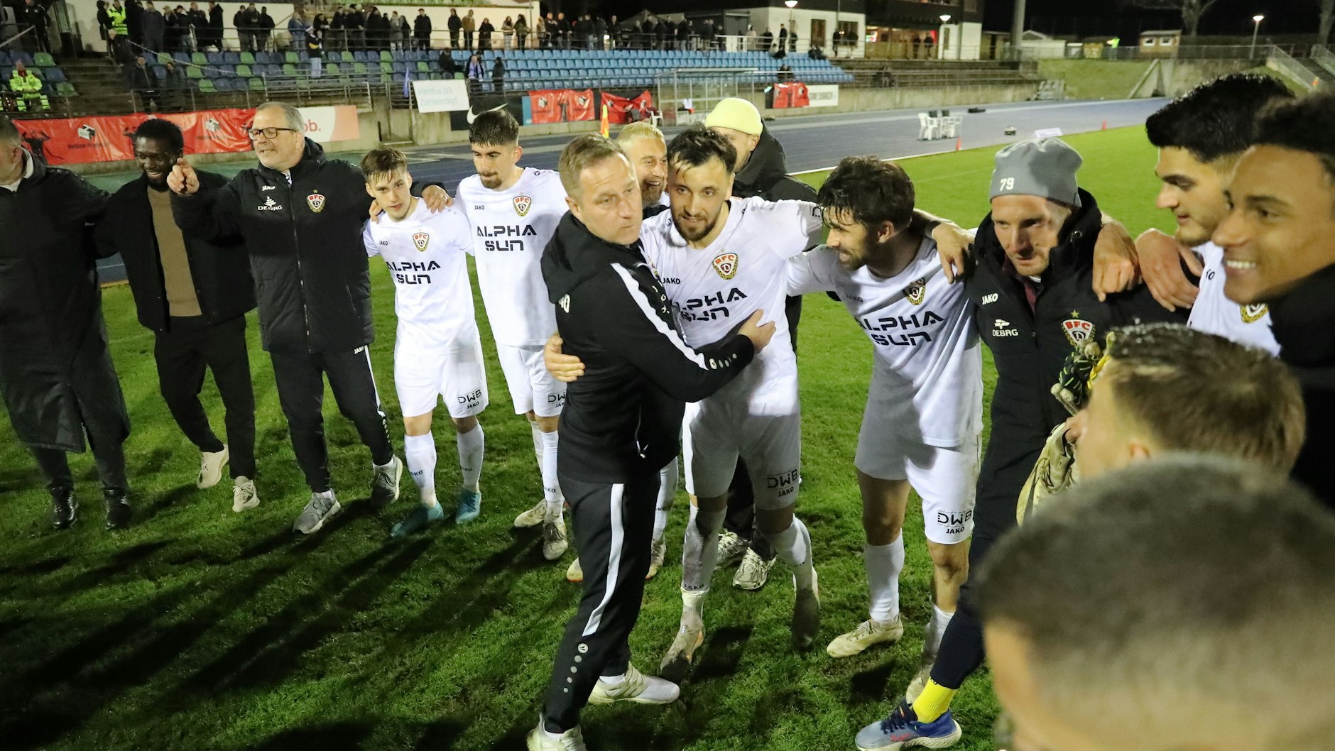 BFC-Trainer Dennis Kutrieb feiert nach dem Sieg in Zehlendorf im Spielerkreis, umarmt Rufat Dadashov, David Haider ist nicht weit weg.