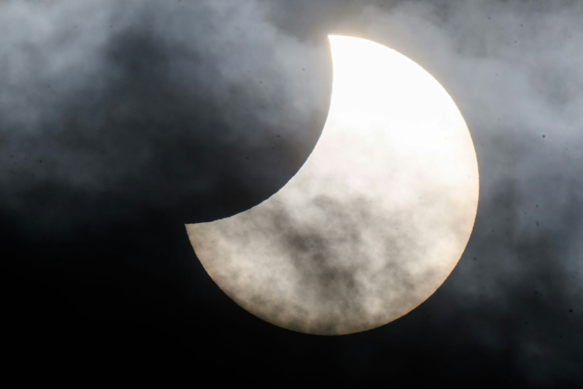 Eine partielle Sonnenfinsternis ist zwischen Wolken am Himmel über der Region Hannover zu sehen.