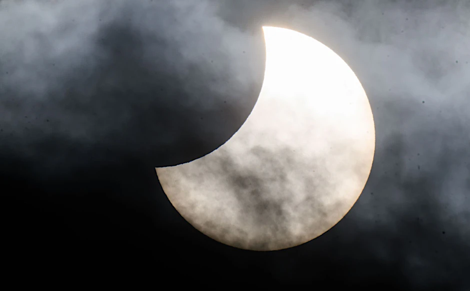 Eine partielle Sonnenfinsternis ist zwischen Wolken am Himmel über der Region Hannover zu sehen.