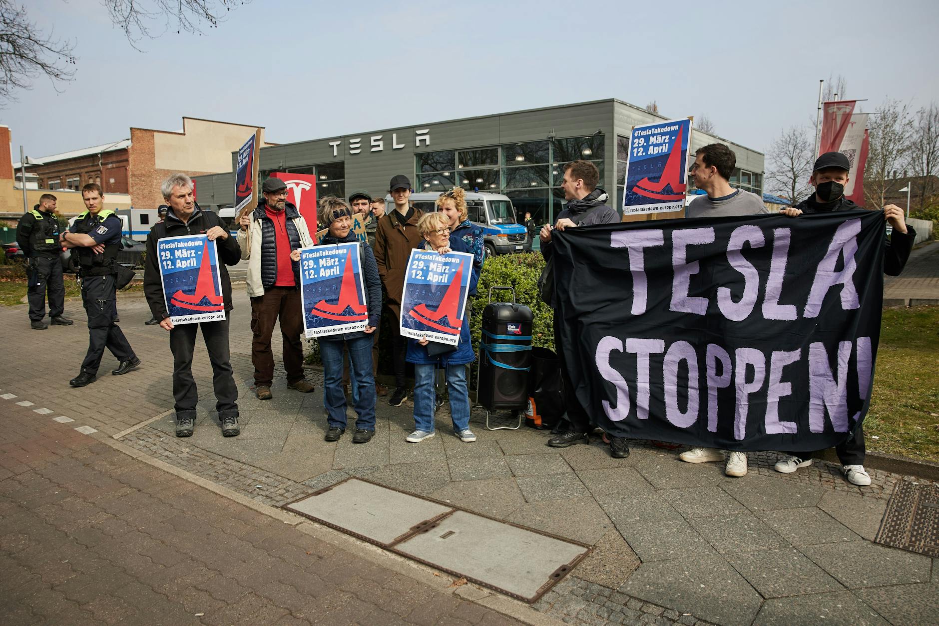 Etwa zehn Menschen protestieren im Rahmen des globalen Protesttages „TeslaTakedown“ vor einem Tesla Store in Berlin-Reinickendorf.