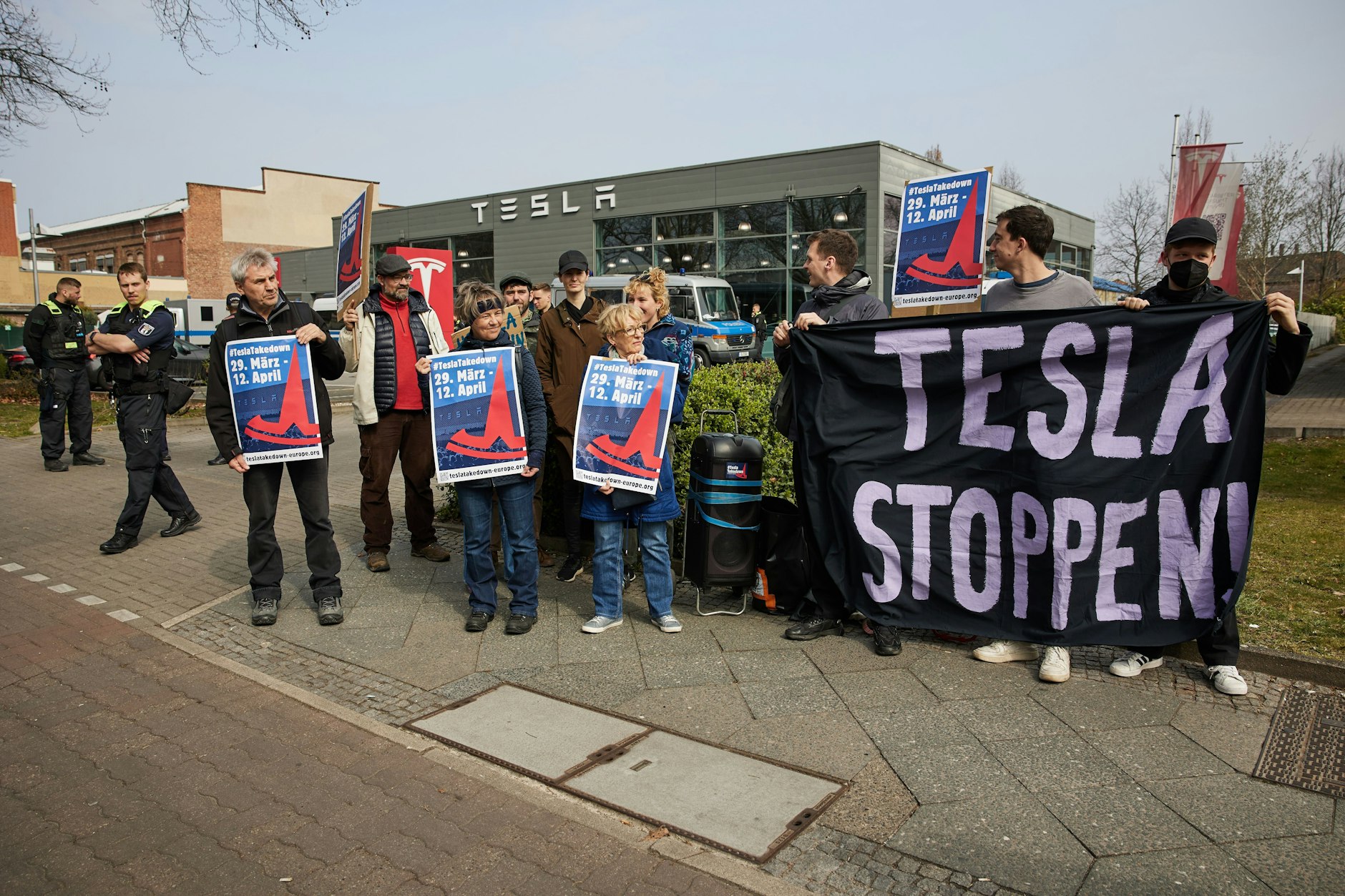 Etwa zehn Menschen protestieren im Rahmen des globalen Protesttages „TeslaTakedown“ vor einem Tesla Store in Berlin-Reinickendorf.