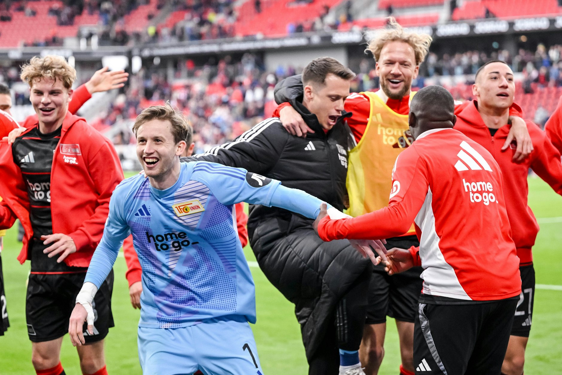 Torwart Frederik Ronnow führt die Jubeltraube der Spieler des 1. FC Union nach dem Sieg beim SC Freiburg an.