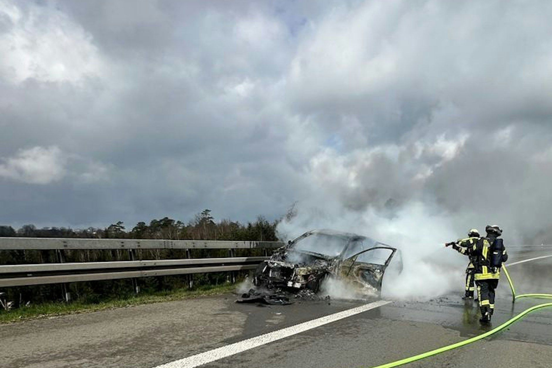 Feuerwehrleute löschen auf der Autobahn 1 den brennenden BMW.