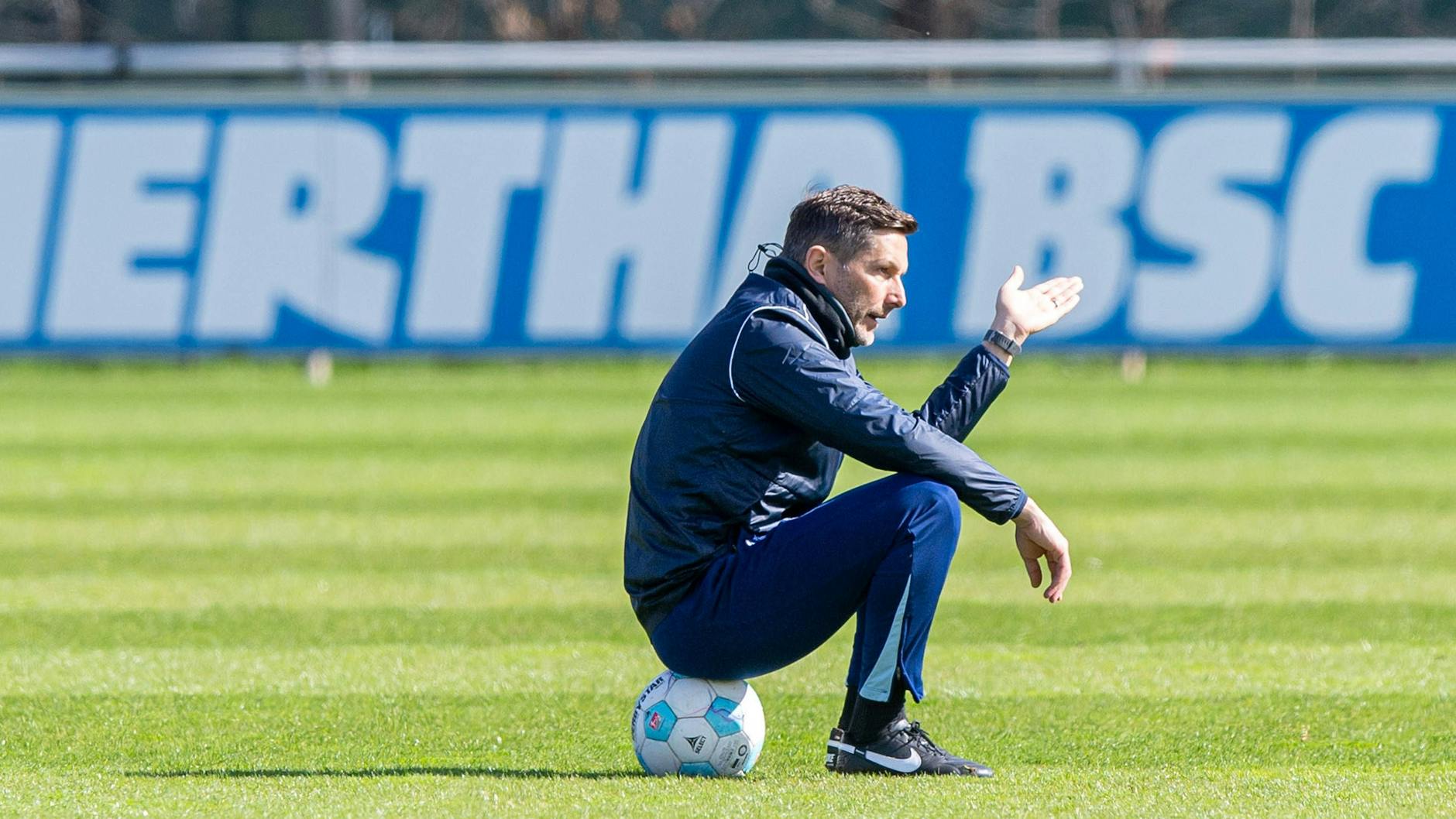Herthas Coach Stefan Leitl sitzt während des Trainings auf dem Ball und gestikuliert.