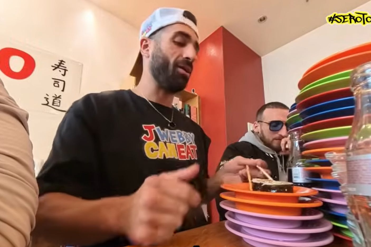 Sero (hinten) und J. Webby (vorne) stapeln jede Menge Sushi-Teller vor sich.