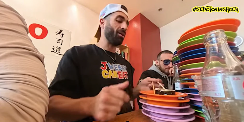 Sero (hinten) und J. Webby (vorne) stapeln jede Menge Sushi-Teller vor sich.