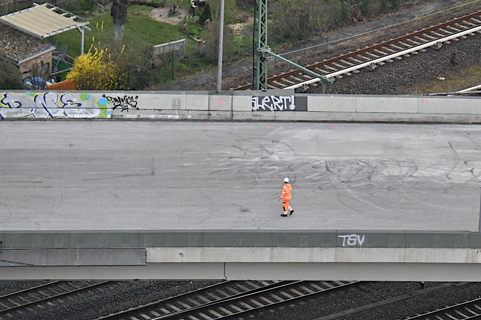 Ein Arbeiter steht auf der gesperrten Ringbahnbrücke der A100. Im Hintergrund sind Kleingärten zu sehen. Unter der aus Sicherheitsgründen gesperrten Autobahnbrücke ist seit vergangener Woche auch der S-Bahn-Verkehr unterbrochen.