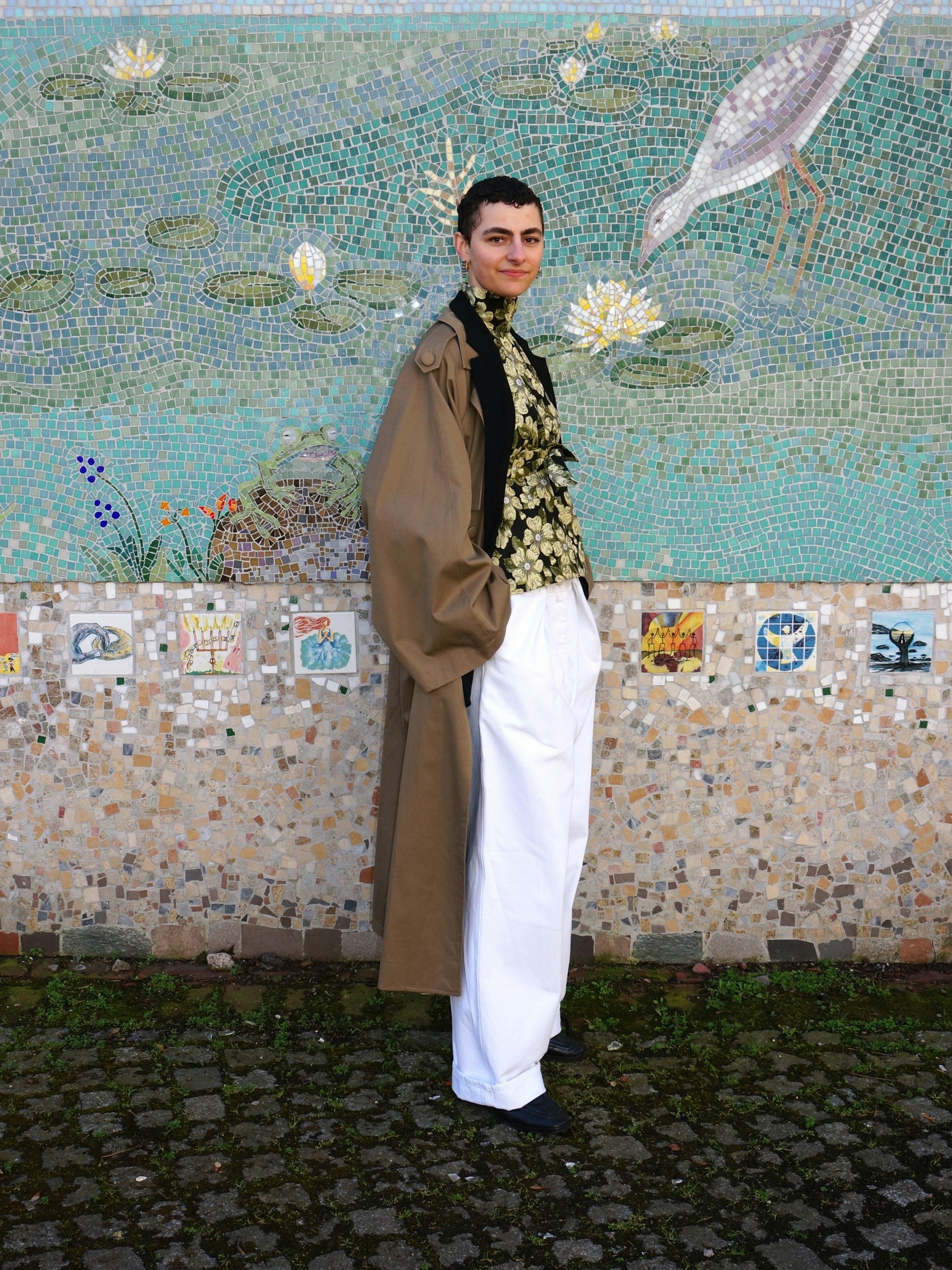 Louisa wohnt in Berlin und arbeitet als Brandmanagerin für den Modedesigner William Fan. Entsprechend setzt sich ihr Outfit vor allem aus eleganten Teilen ihres Arbeitgebers zusammen:&nbsp; Top, Blazer und Trenchcoat in Dunkelbeige von William Fan, dazu eine schneeweiße Vintage-Hose von Dries Van Noten und Loafer von Bottega Veneta.