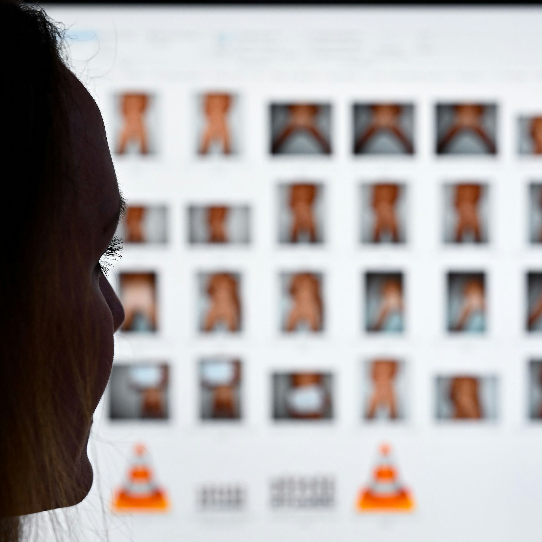 Eine Staatsanwältin sitzt vor einem Monitor mit Fotos (Symbolfoto). Auch für Ermittler, die an solchen Fällen beteiligt sind, hat die Seite Kidflix eine völlig neue Dimension.