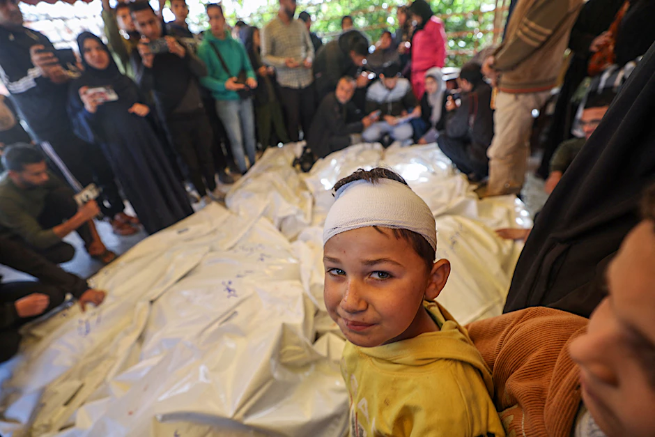 Noch einmal überlebt: Ein verletzter palästinensischer Junge vor verdeckten Leichen und trauernden Angehörigen am Mittwoch in Chan Junis im Gazastreifen.