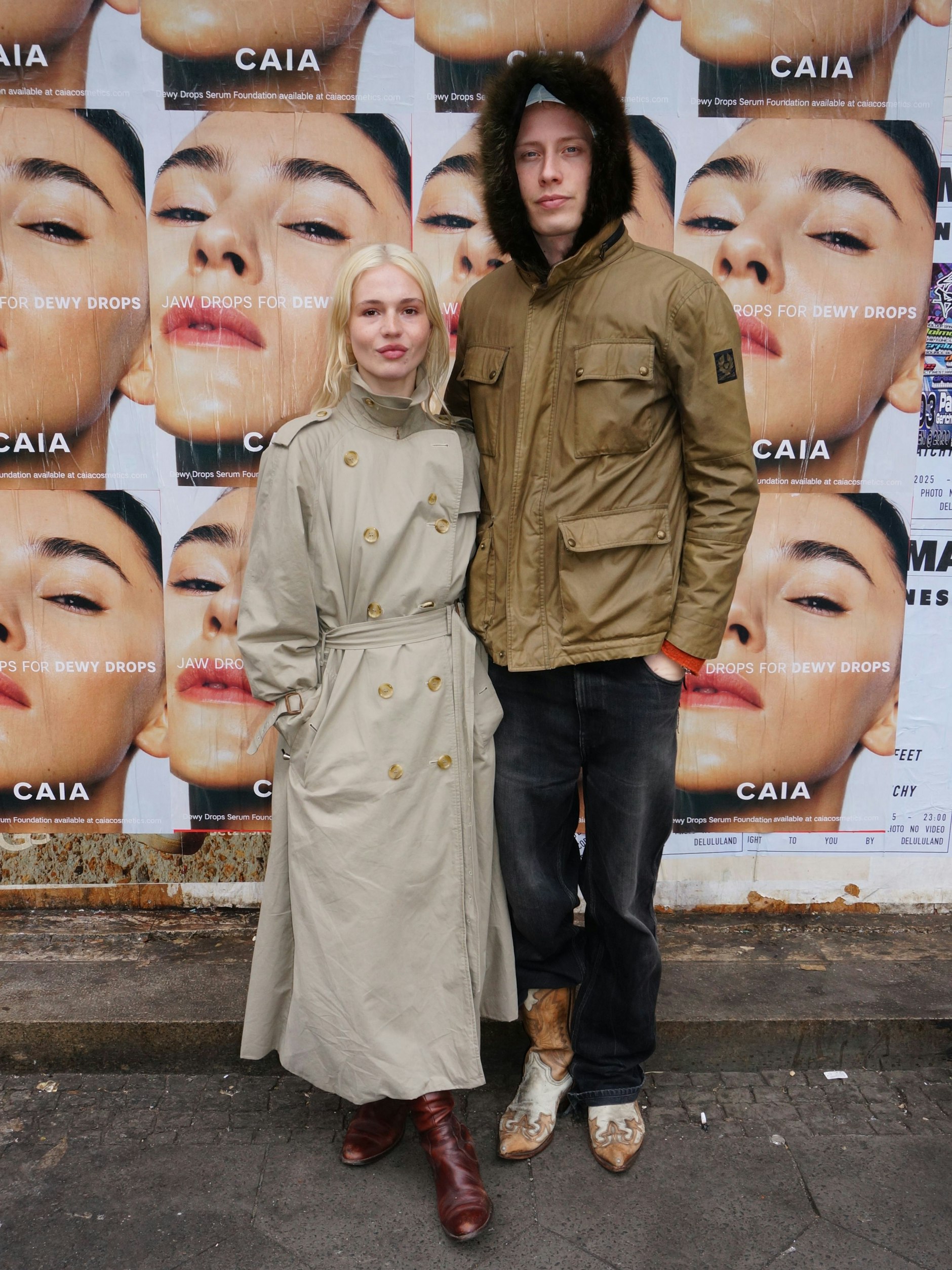Dieses schöne Paar treffen wir in der Nähe des Naturkundemuseums. Anna wohnt in Paris, wo sie als Mode-Producerin arbeitet. Das tut sie manchmal auch in Berlin, wo sie zuletzt die Fashionshow ihres Freundes Laurin Schuler (rechts im Bild) auf der hiesigen <a href="https://www.berliner-zeitung.de/topics/fashion-week">Fashion Week</a> produzierte. Anne trägt einen locker geschnittenen Burberry-Trenchcoat aus den 80er-Jahren, den sie einst in einem Vintage-Store in Marais erstand. Zwischenzeitlich war das gute Stück abhandengekommen, fand sich jedoch kürzlich in einer Kiste wieder. Zum Glück. Dazu trägt die Wahlpariserin Reiterstiefel, Strumpfhose und knappe Panties. Laurin darf mit aufs Foto, auch wenn er keinen Trench trägt, sondern eine Wachsjacke von Papa samt Echtpelzkapuze von Anna, aus dem Leim gehende Cowboy-Boots und eine Hose von Calvin Klein.