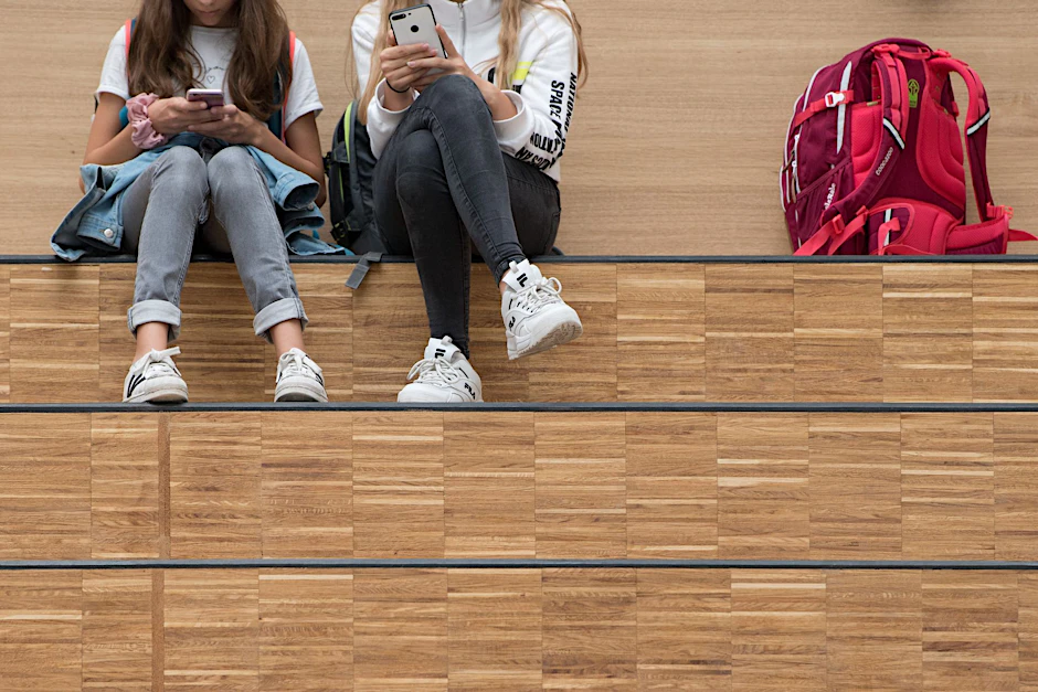 Schülerinnen sitzen im Foyer ihrer Schule.