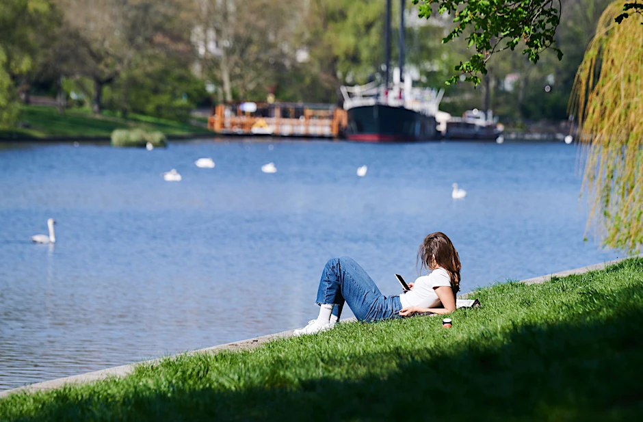 Eine Frau liegt am Landwehrkanal in der Sonne. In Berlin gibt es so viele Möglichkeiten für kostenlose Ausflüge an einem sonnigen Sonntag. 