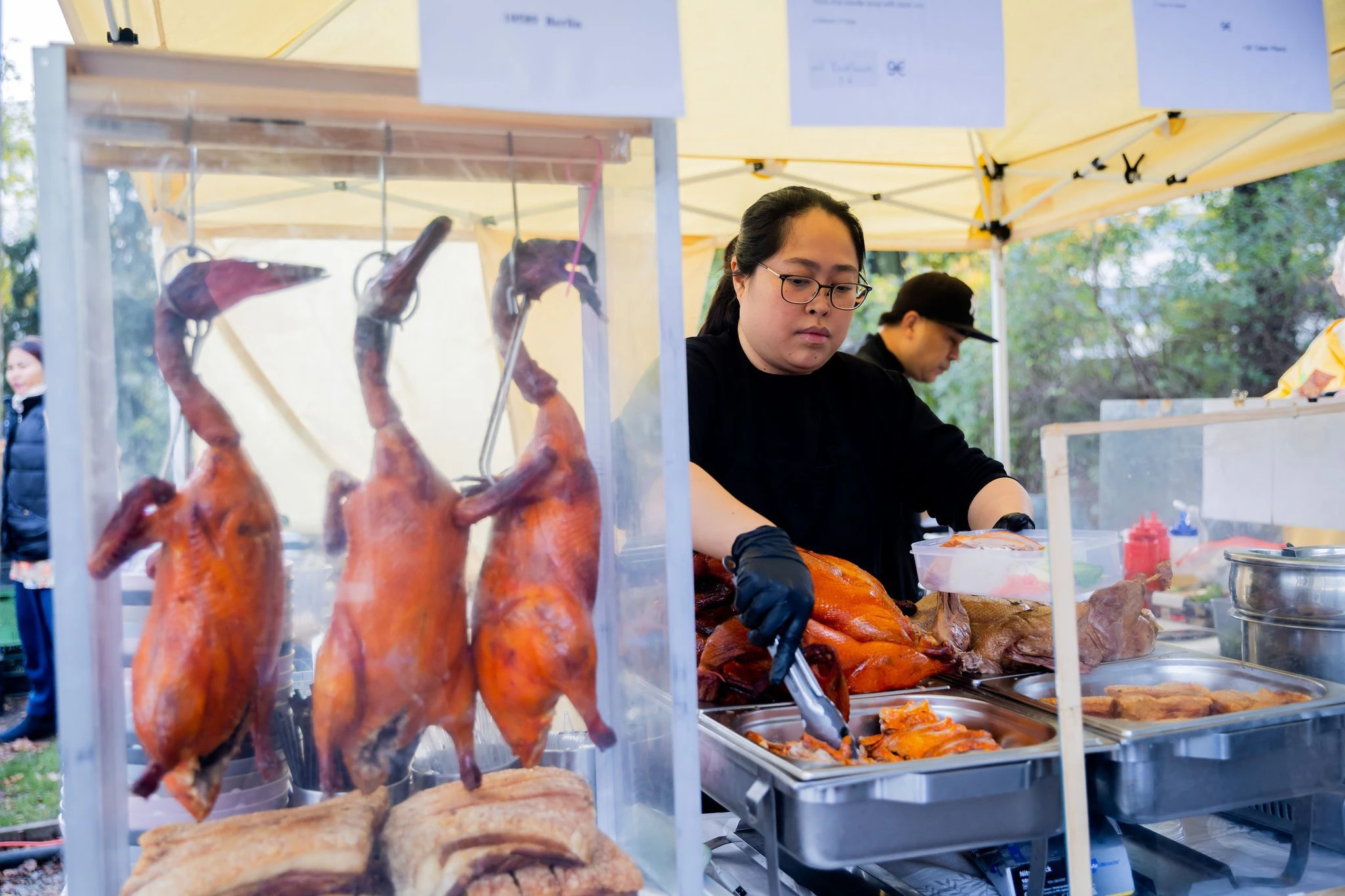Tipa Pitibut, Köchin, bereitet auf dem Thaimarkt im Preußenpark ein Gericht mit gegrillter Ende und knusprigem Schweinebauch zu.
