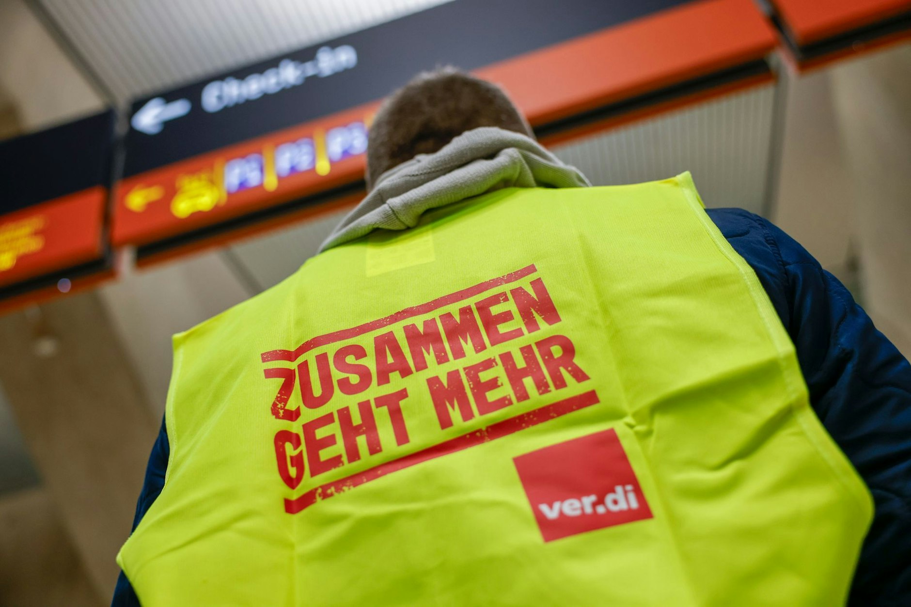 Ein Mann, der eine Warnweste mit der Aufschrift “Zusammen geht mehr“ trägt, steht im Terminal des Flughafens Köln Bonn. (Symbolfoto)