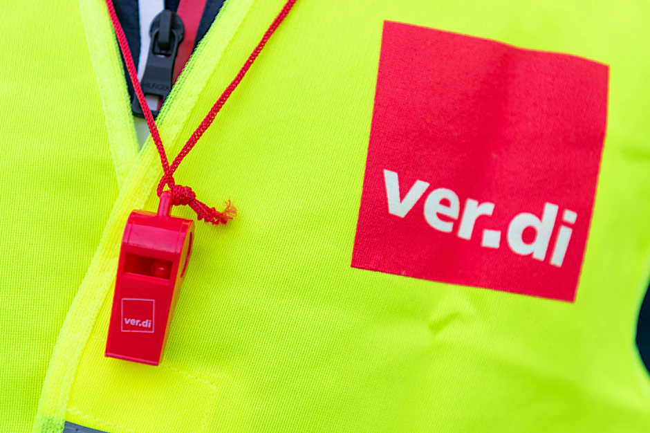Ein Streikender trägt eine Warnweste mit dem Verdi-Logo und eine rote Trillerpfeife: Auch wenn es eine Tarifeinigung im öffentlichen Dienst gab, ruht noch nicht der Streikwille in anderen Branchen.
