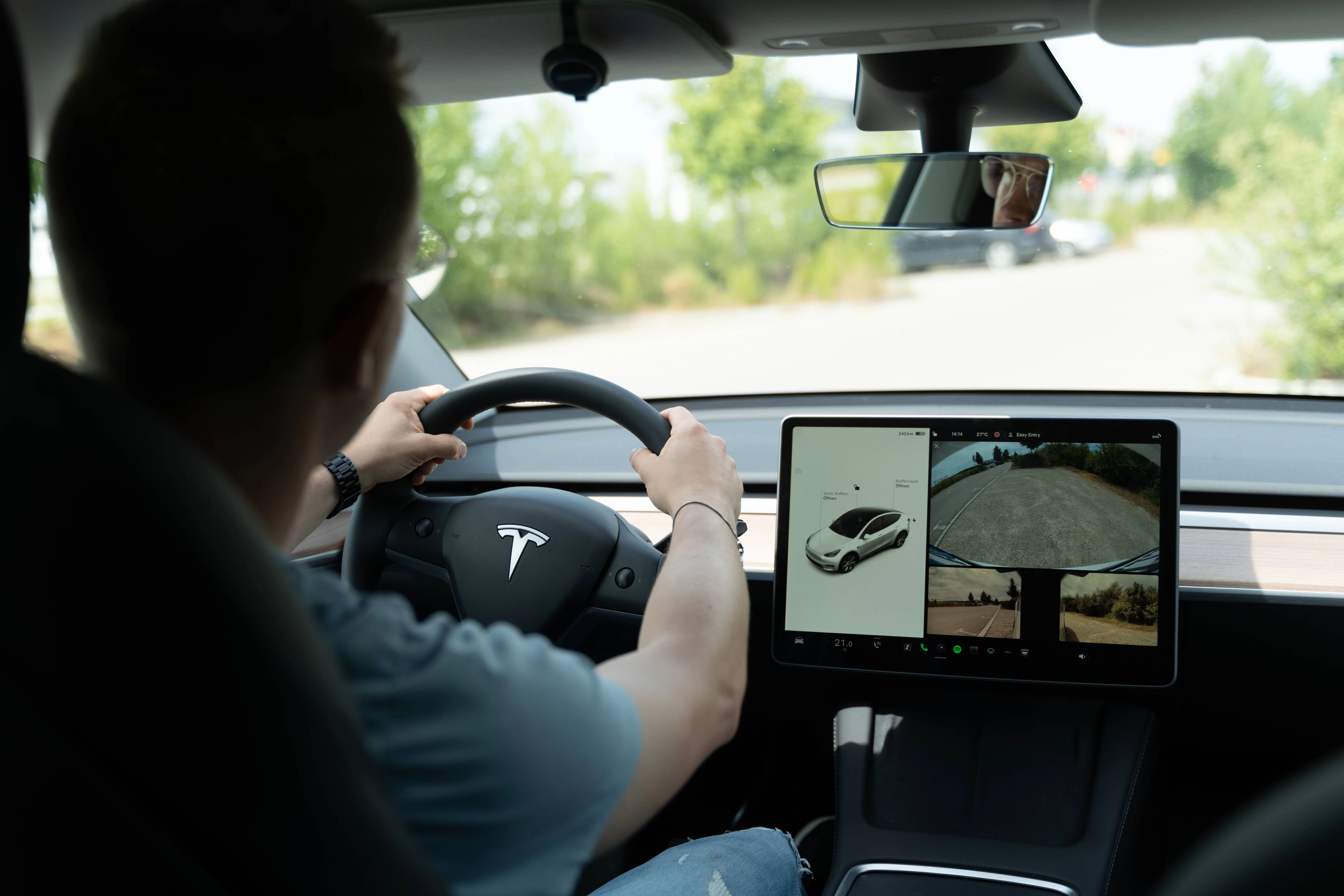 Ein Mann am Steuer eines Tesla. Der Autopilot der Autos soll immer wieder Probleme haben