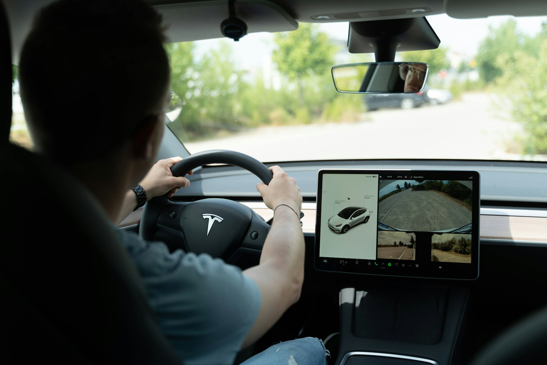 Ein Mann am Steuer eines Tesla. Der Autopilot der Autos soll immer wieder Probleme haben