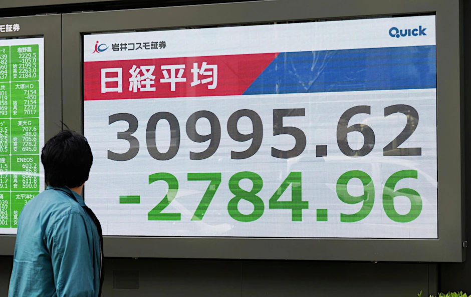 Eine Person geht an einer elektronischen Börsentafel in Tokio vorbei.