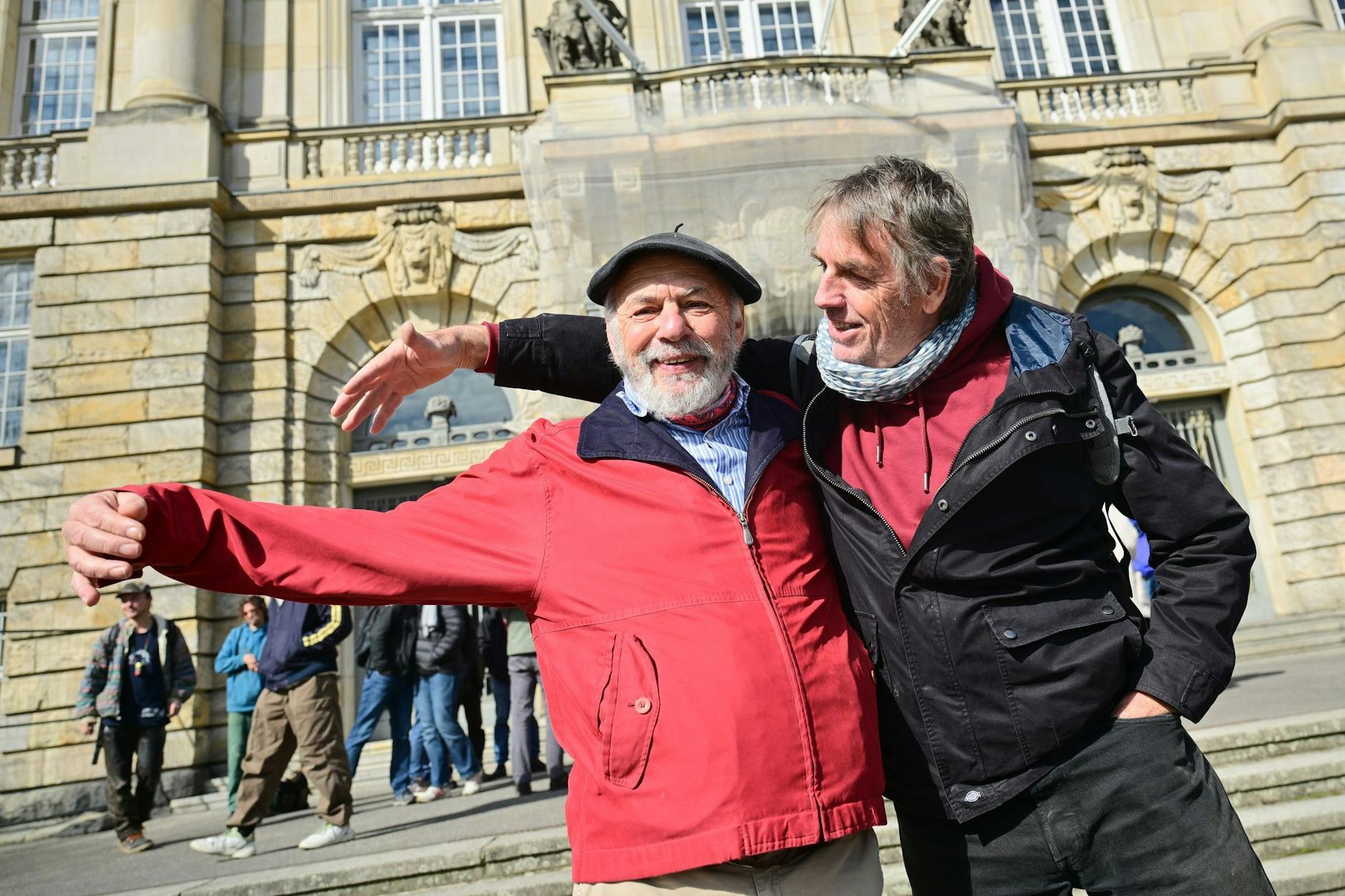 Peter K. (l) und Thomas W. stehen nach der Urteilsverkündung vor dem Berliner Kammergericht und strecken ihre Arme so aus, als würden sie einen Dritten umarmen. Damit schließen sie den dritten damals Untergetauchten ein, der an Krebs verstorben ist.
