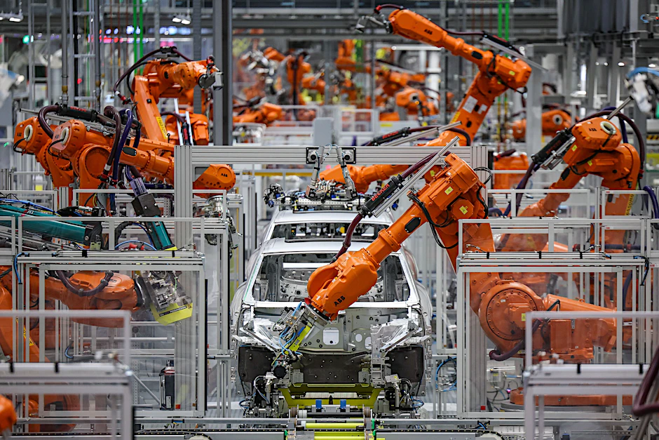 Industrieroboter arbeiten an der Karosserie für einen vollelektrischen Porsche Macan im Werk Leipzig.