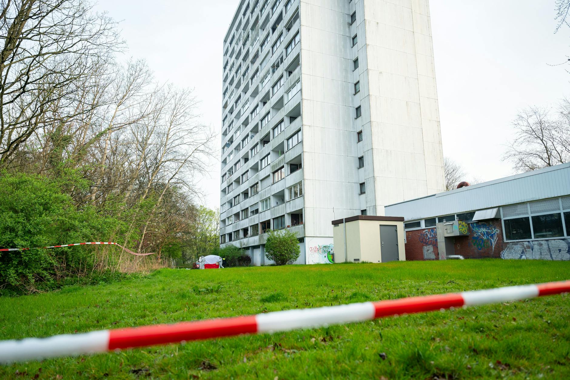 Beamte der Spurensicherung ermitteln neben dem abgesperrten Hochhaus. Ein junger Mann ist in der Nacht in Hamburg-Wilsdorf vom Balkon eines Hochhauses in den Tod gestürzt. Es gebe Hinweise auf ein Fremdverschulden, sagte ein Sprecher der Polizei.