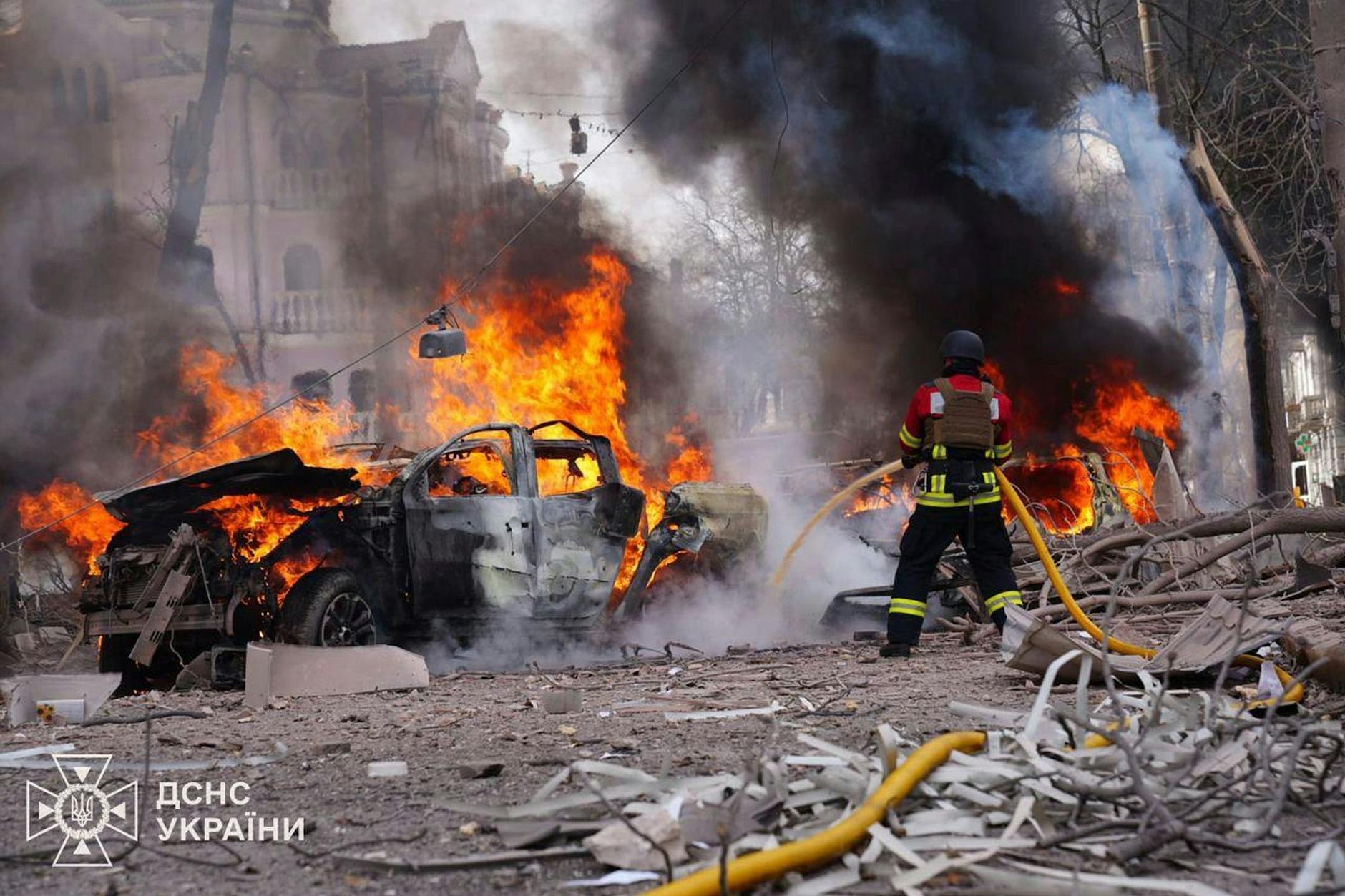Ukraine, Sumy: Feuerwehrleute löschen nach dem russischen Raketenangriff auf das Zentrum der Stadt ein brennendes Auto.