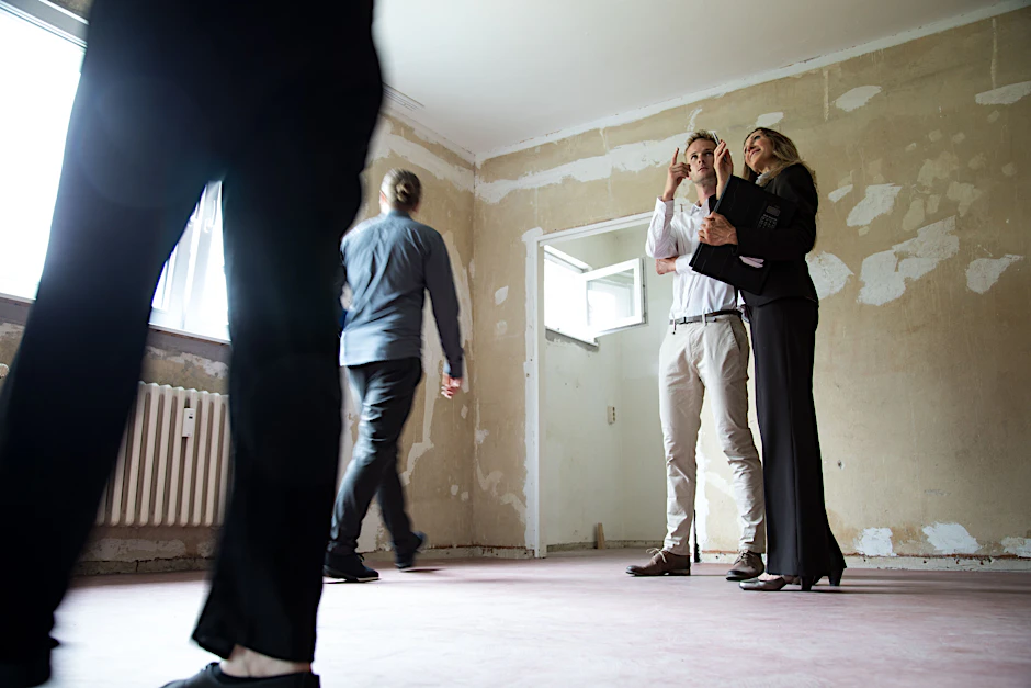 Eine Maklerin zeigt Interessenten in Berlin eine leerstehende, unsanierte Wohnung.