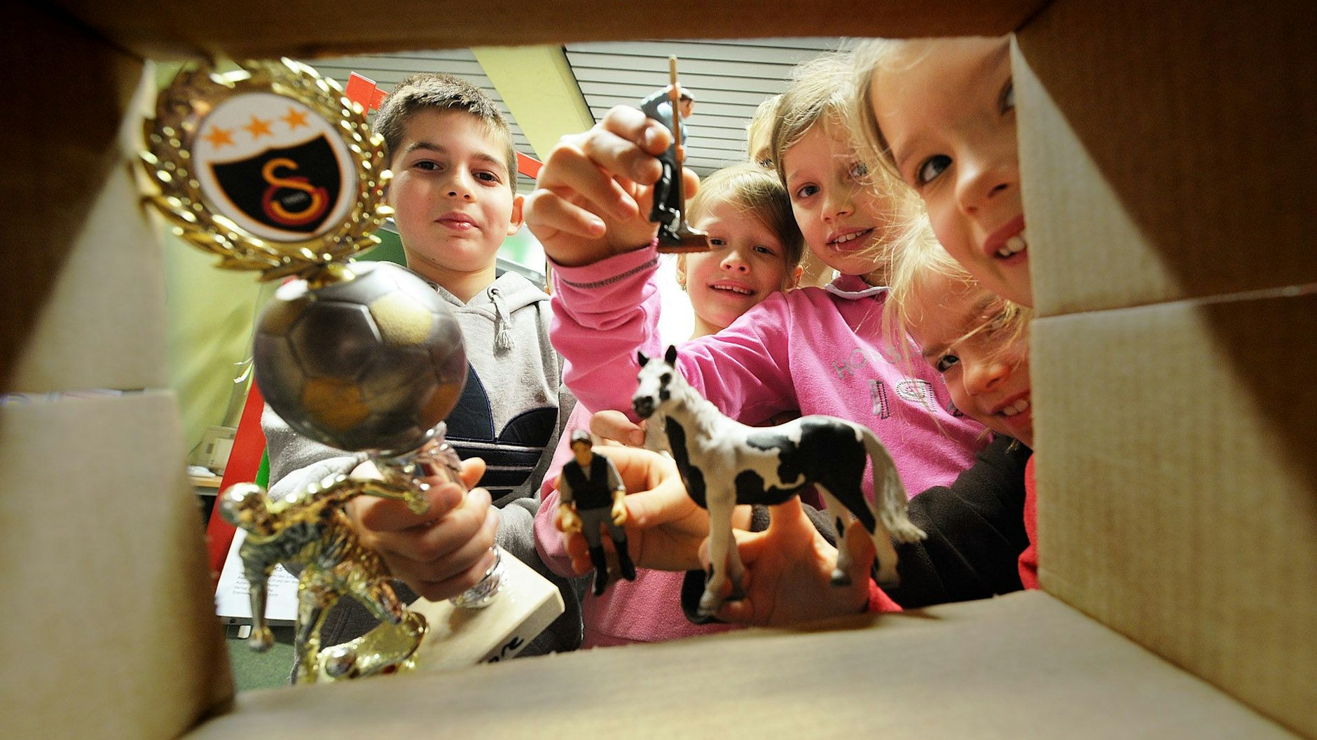 Kinder basteln eine Lesekiste zu einem Buch, indem sie Gegenstände, die in der Geschichte vorkommen, in einen Schuhkarton packen.