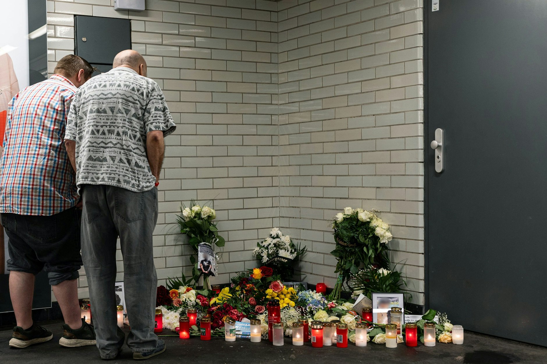 Menschen stehen im U-Bahnhof Sophie-Charlotte-Platz vor einer mit Blumen und Kerzen dekorierten Trauerstätte. Hier starb ein Berliner nach einer Messerattacke.
