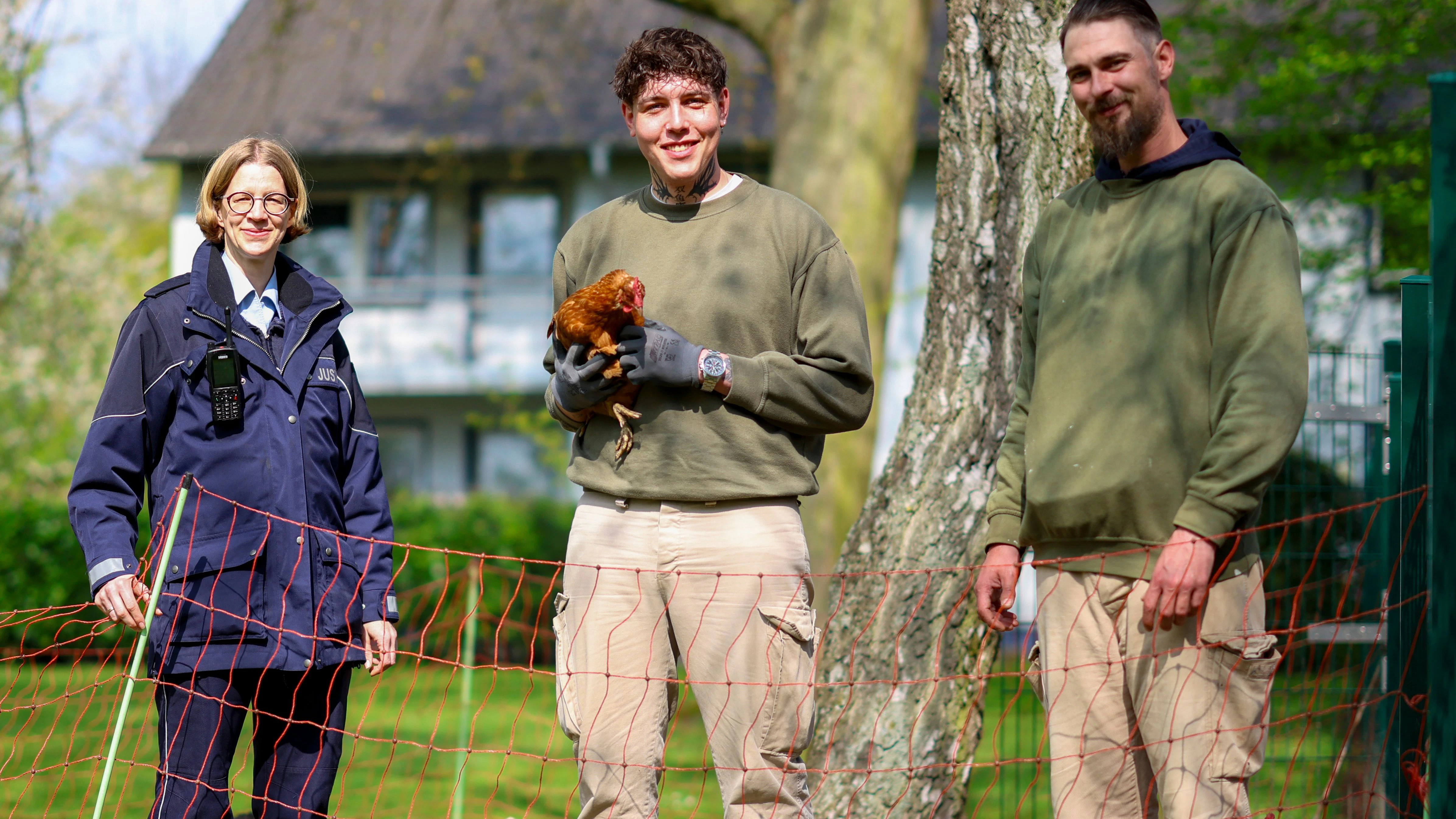 Die Vollzugsbeamtin Anika Schäfer ist für das Hühnerprojekt der JVA zuständig. Die Häftlinge Ryan (li.) und Manuel kümmern sich um das geschundene Federvieh. 