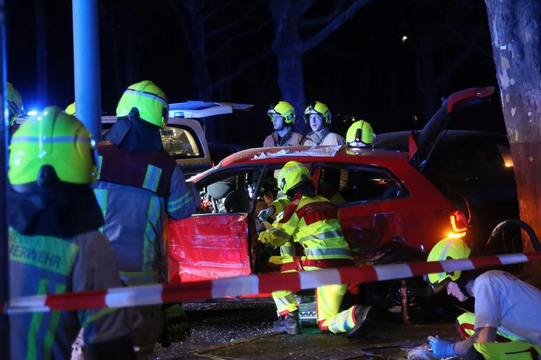 Feuerwehrleute nach dem Raserunfall am verunglückten Wagen. 