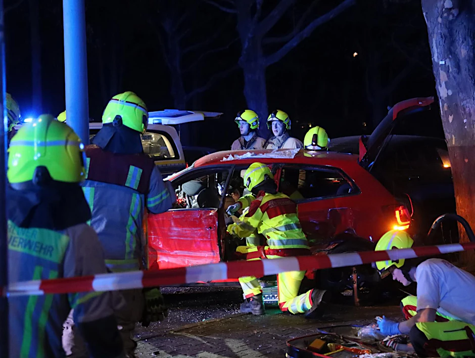 Feuerwehrleute nach dem Raserunfall am verunglückten Wagen. 