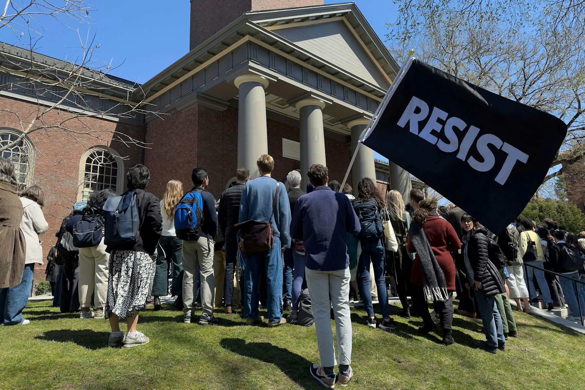 Studenten, Dozenten und Mitglieder der Harvard-Universität versammeln sich zu einem Protest in Cambridge, zu sehen ein Schild mit der Aufschrift „Resist“.