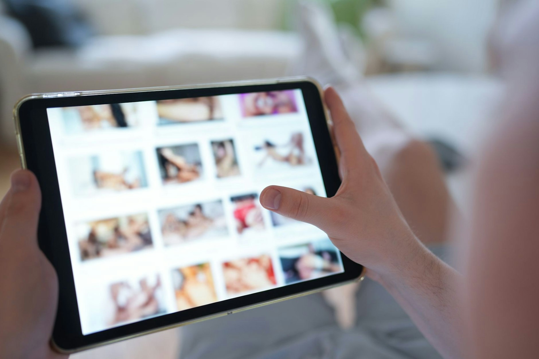 Ein junger Mann schaut sich auf einem Smartphone eine Porno-Internetseite an. Immer mehr Frauen und Mädchen werden Opfer von Deepfake-Pornos.