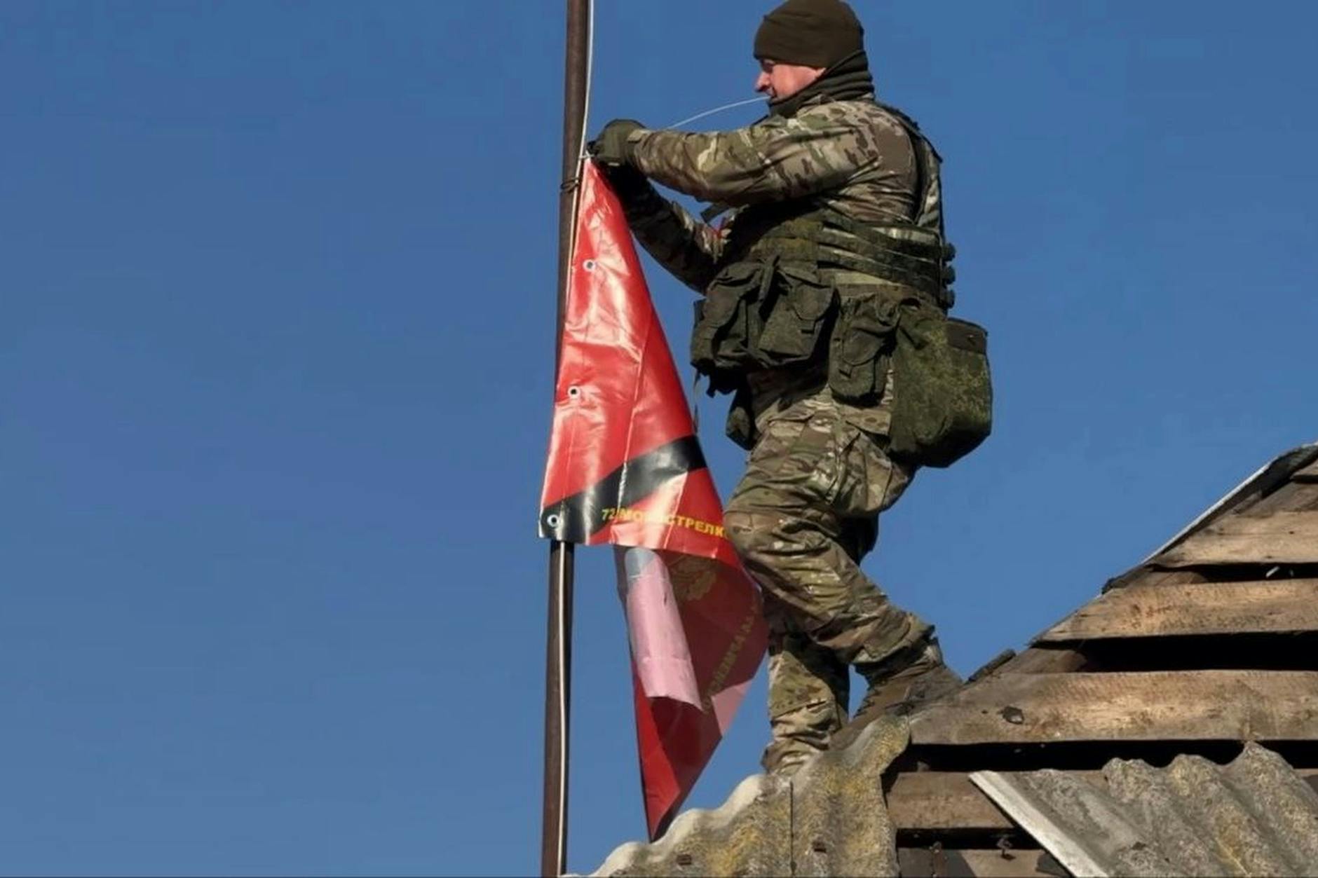 Un soldado ruso se prepara para izar una bandera en una casa después de que las tropas rusas capturaran una aldea en la región de Kursk.