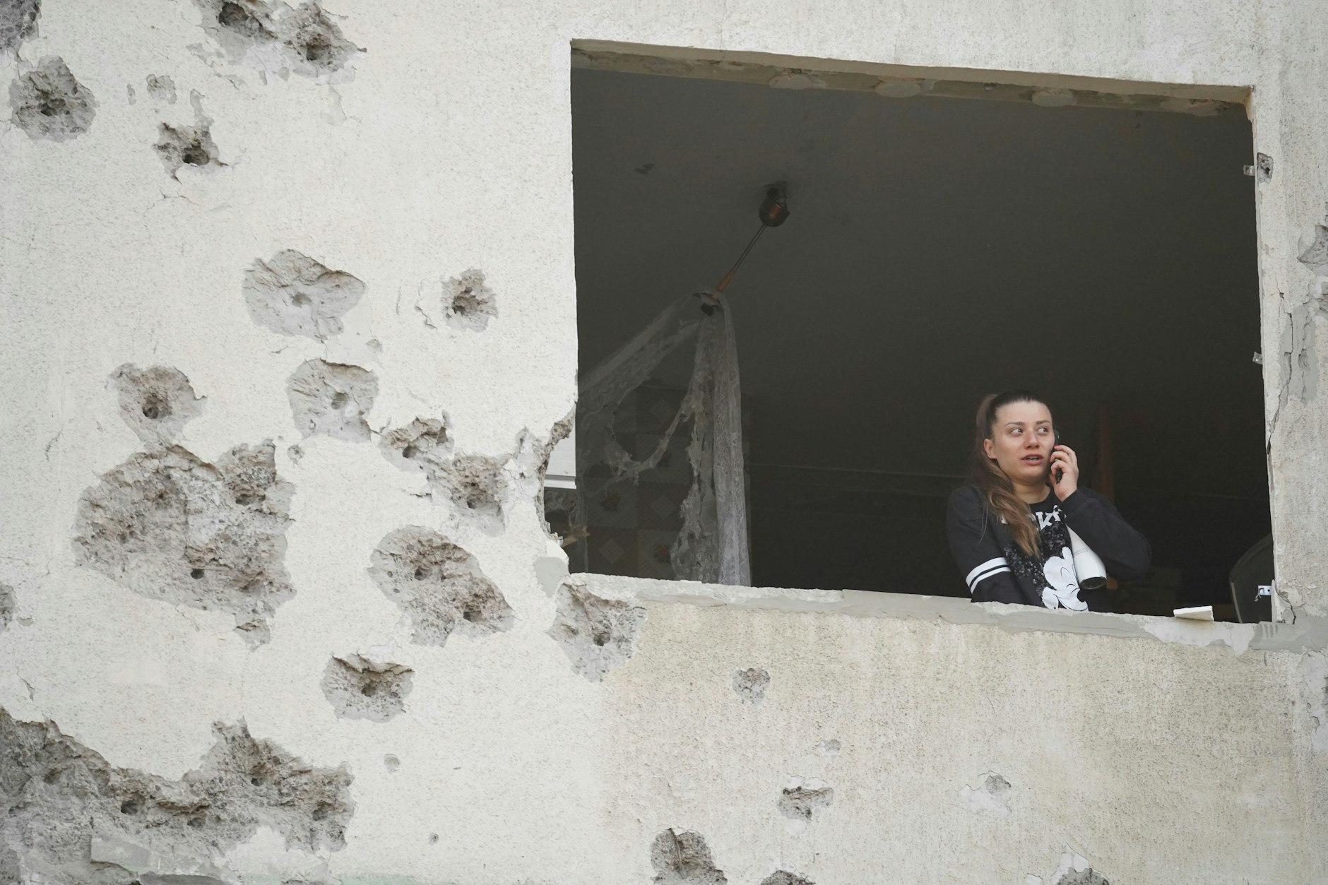 18.04.2025, Ukraine, Charkiw: Eine Frau blickt aus dem Fenster ihrer nach einem russischen Angriff beschädigten Wohnung.