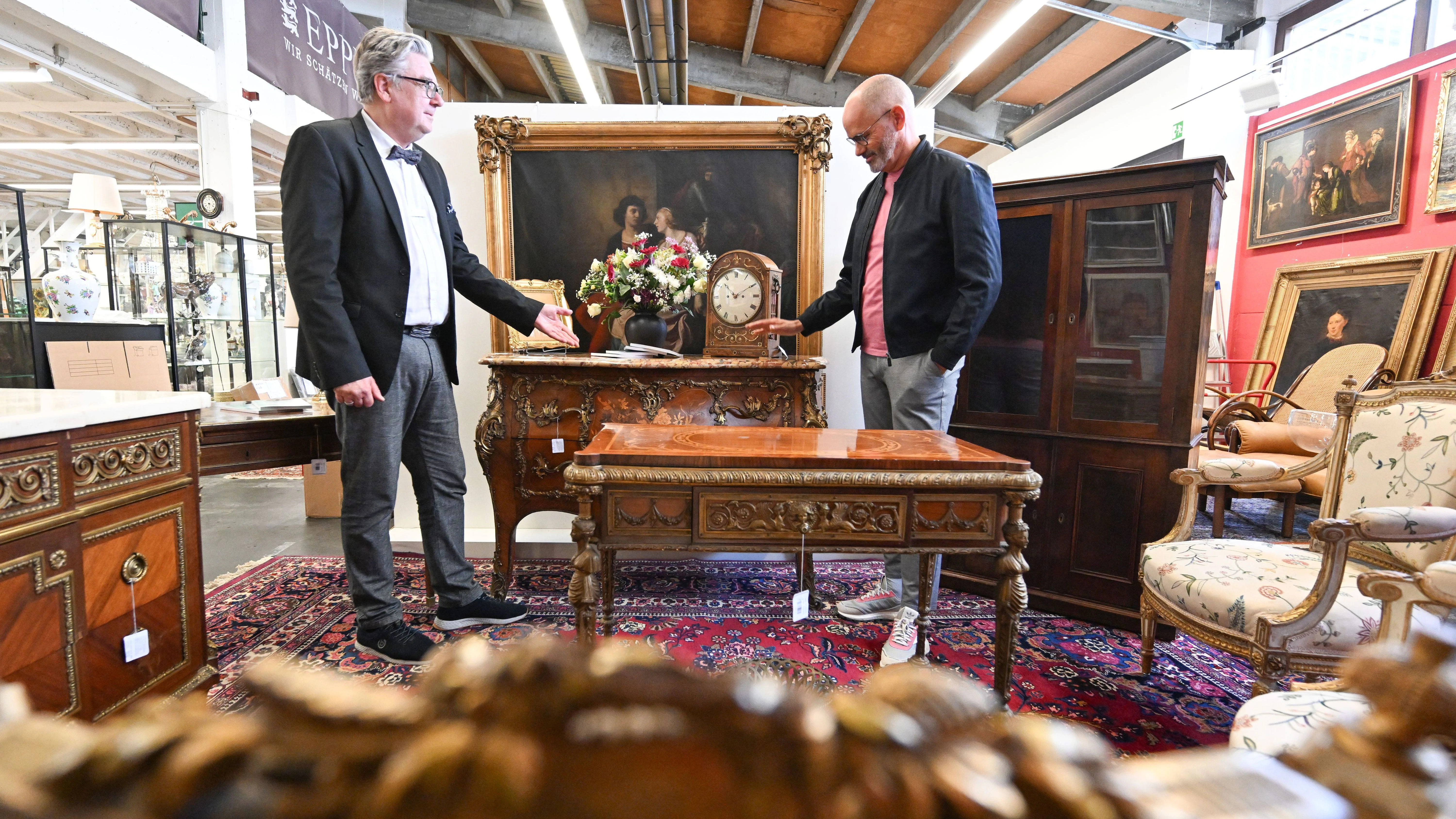 Der Auktionator Rene Waldrab (l.) und der Antiquitätenexperte Jose Juan Martinez-Garcia stehen im Auktionshaus Eppli bei antiken Möbeln des Entertainers Harald Juhnke.
