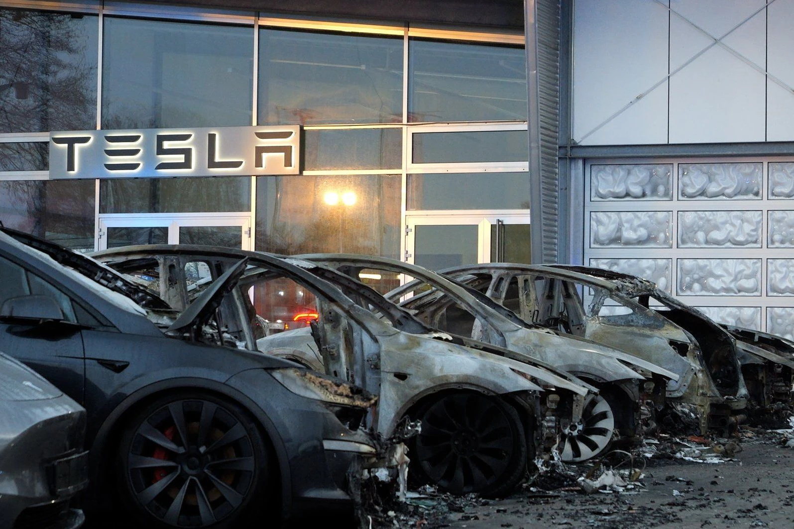 Ausgebrannte Elektroautos sind vor einem Tesla-Autohaus in Niedersachsen zu sehen.