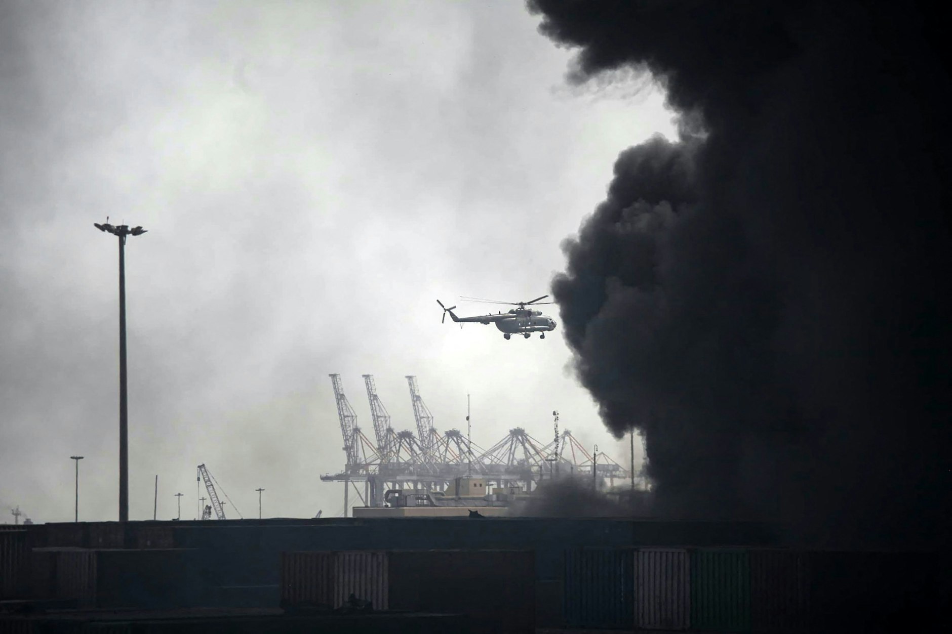 Ein Hubschrauber fliegt am 26. April 2025 über den Rauch, der nach einer Explosion im Hafendock Shahid Rajaee südwestlich von Bandar Abbas in der iranischen Provinz Hormozgan entstanden ist.