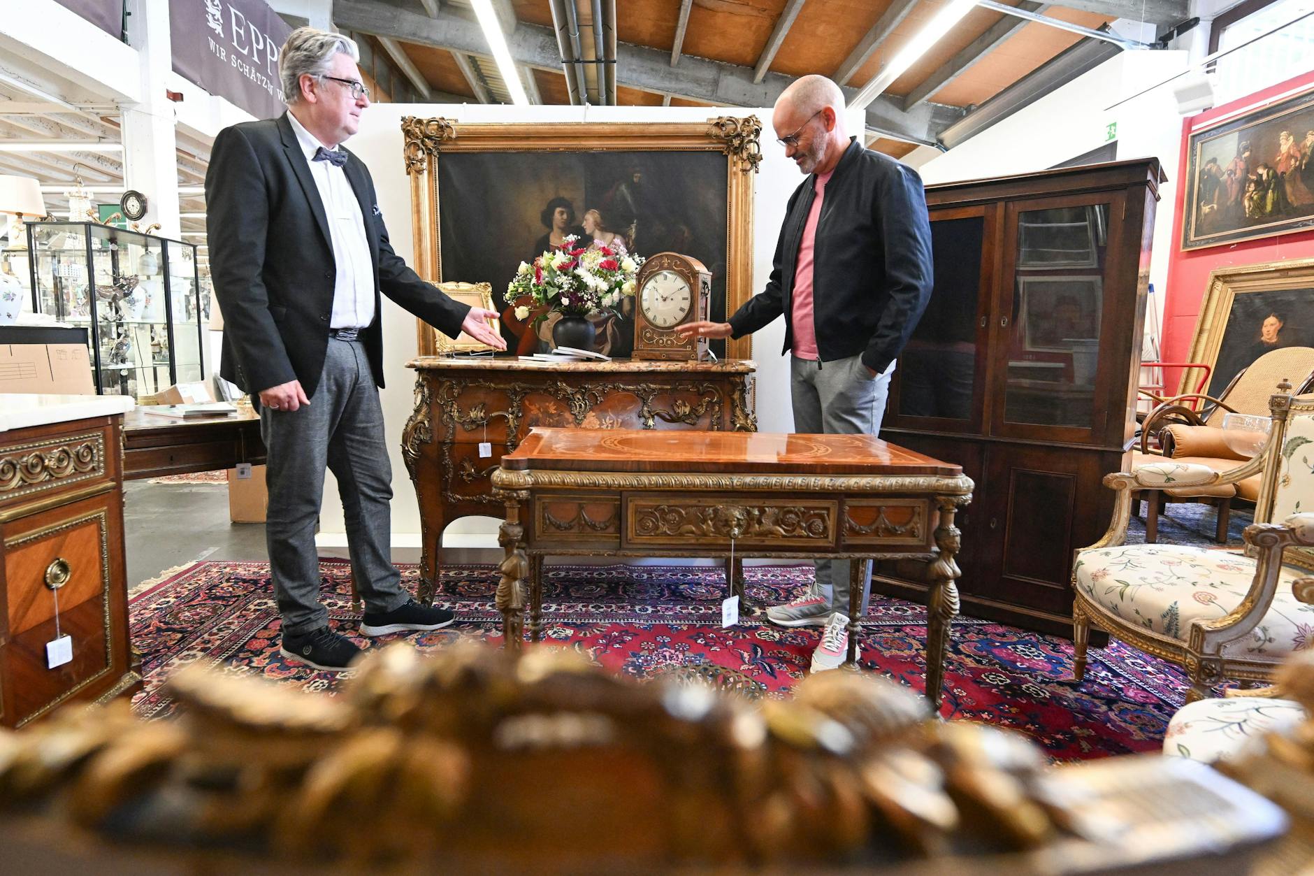 Der Auktionator Rene Waldrab (l) und der Antiquitätenexperte Jose Juan Martinez-Garcia (r) stehen im Auktionshaus Eppli bei antiken Möbeln des vor 20 Jahren verstorbenen Entertainers Harald Juhnke.