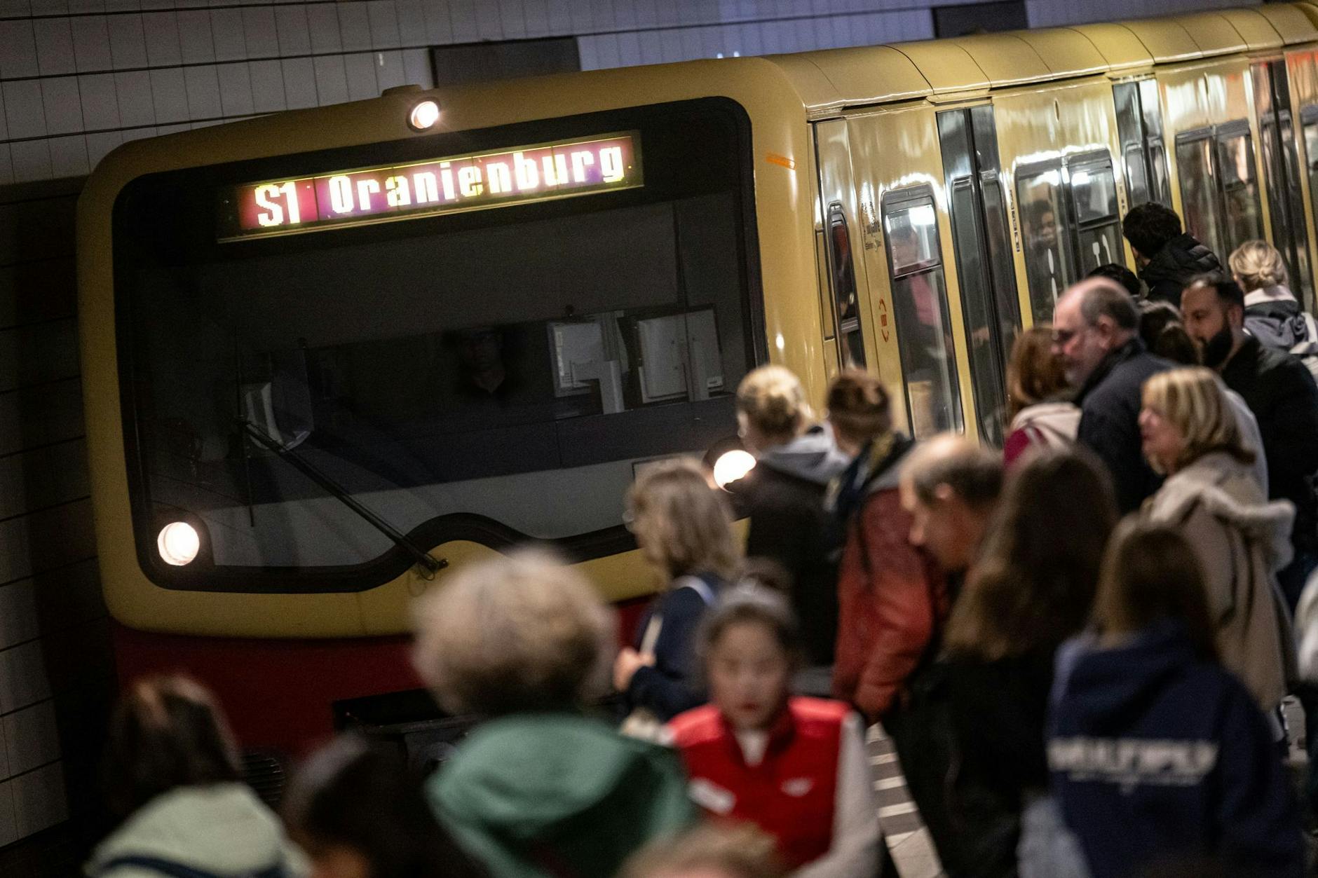 Menschen stehen am S-Bahnhof Friedrichstraße vor der S-Bahn S1 Oranienburg.