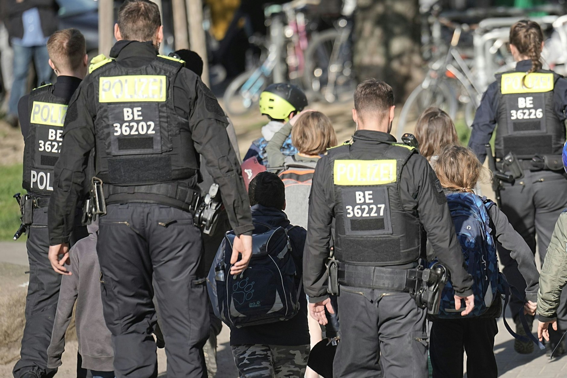 Polizisten geleiten Kinder weg vom Tatort an einer Schule in Berlin-Neukölln.