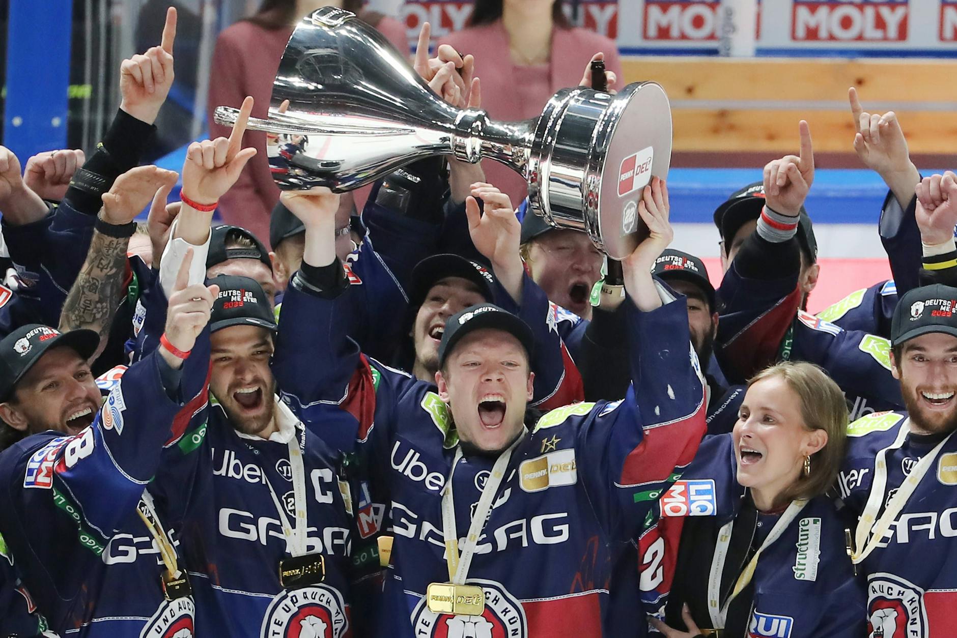 Als Jonas Müller ihn Freitag neben Ina, der Verlobten des im Januar verstorbenen Eisbären-Stürmers Tobi Eder, stemmt, hat der Pokal noch Henkel. Die hat der Pott inzwischen mal wieder eingebüßt.