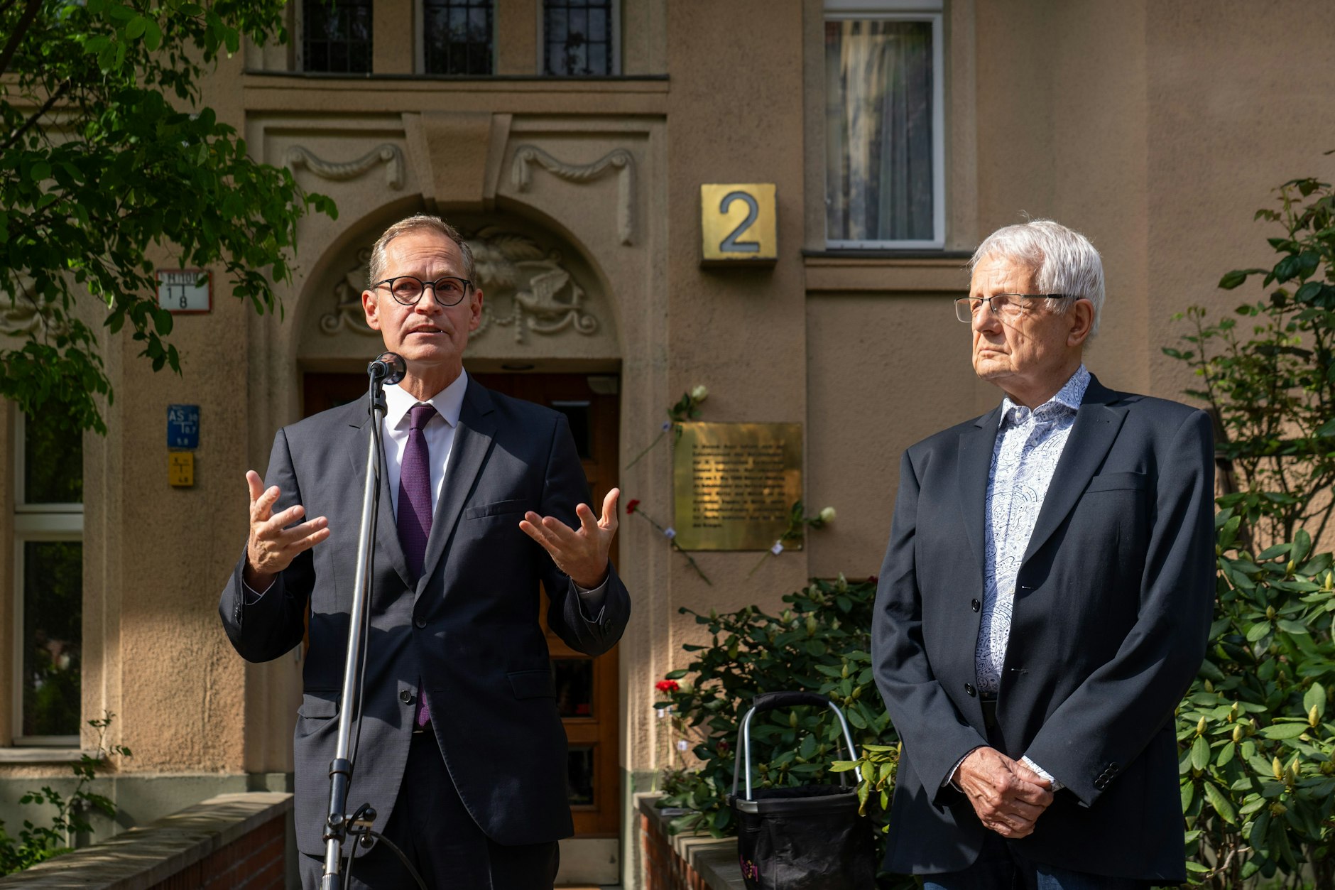 Michael Müller (l.) und der Vorsitzende der Hausgemeinschaft, Joachim Dillinger, eröffneten am Freitag vor dem Wohnhaus am Schulenburgring 2 in Tempelhof die Gedenkfeierlichkeiten zu 80 Jahren Kriegsende.