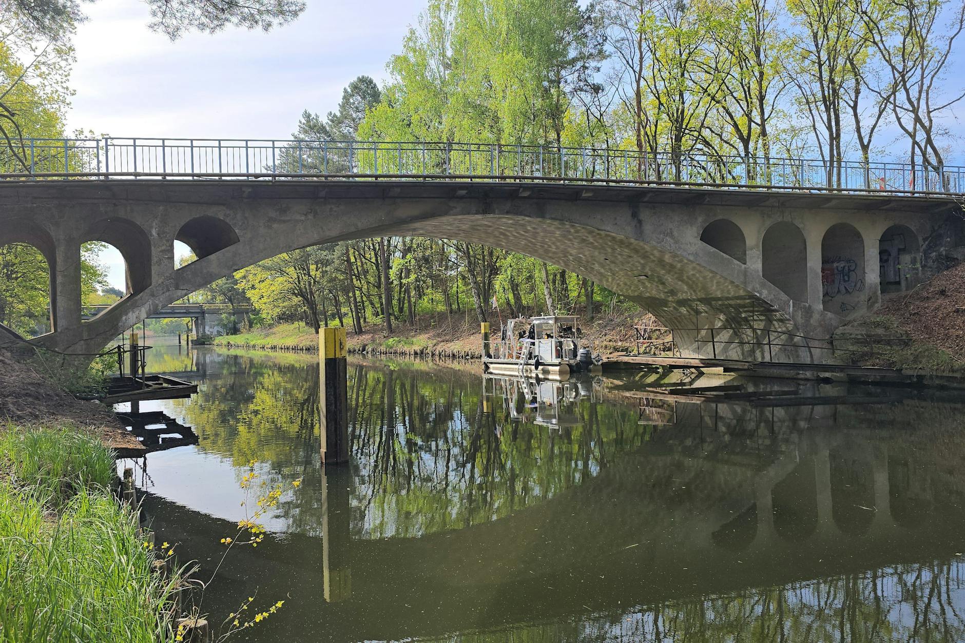 Eine kleine, schwimmende Arbeitsplattform liegt neben einer Brücke am Ufer. Taucher des Kampfmittelräumungsdienstes hatten in der Nähe den verpackten Schädel eines Menschen im Wasser entdeckt.